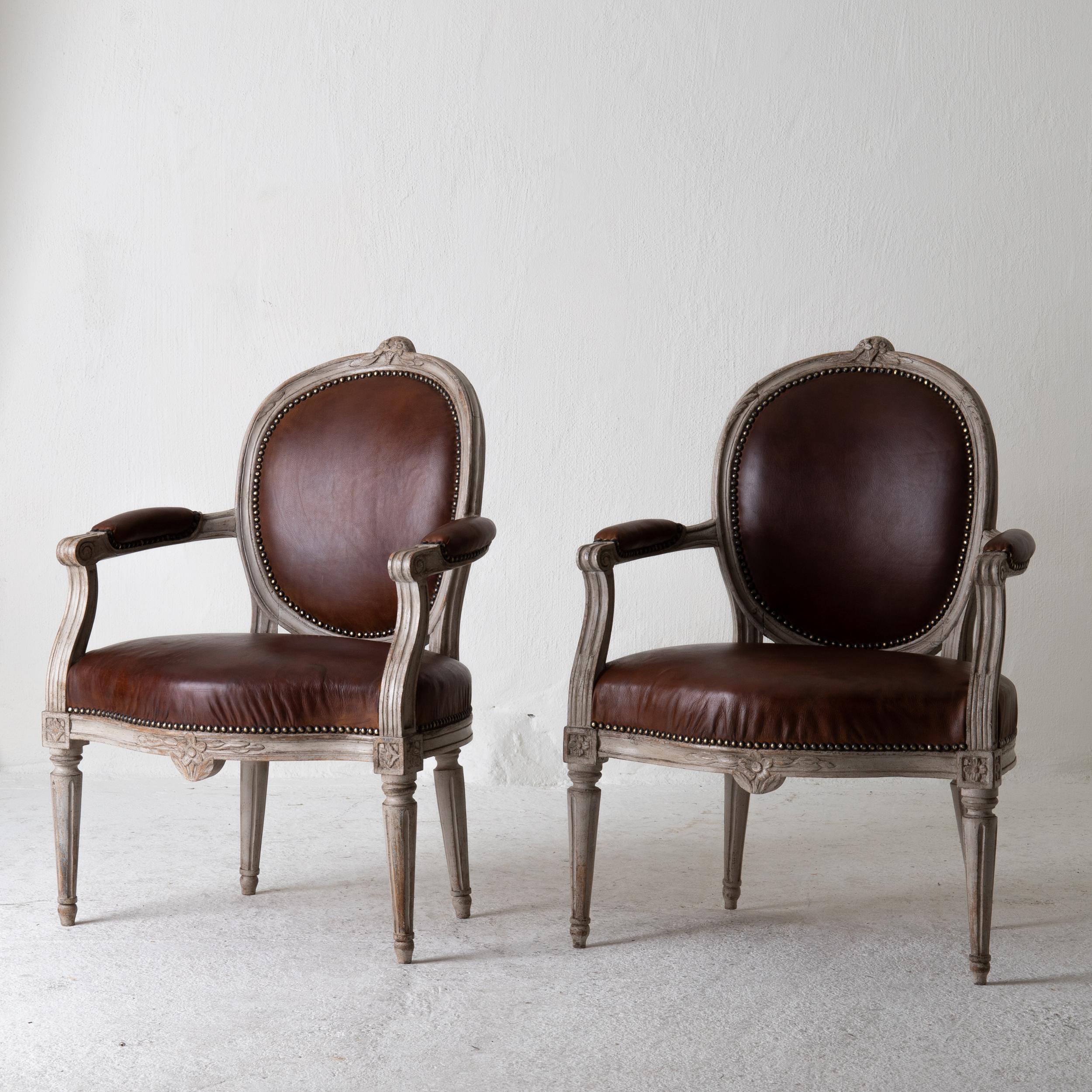 Armchairs Gustavian 1780-1800 Swedish gray frame brown leather, Sweden. A pair of armchairs made during the early Gustavian period in Sweden 1780-1800. Painted in a gray and upholstered on seat, back and armrests in a waxed leather. Beautiful