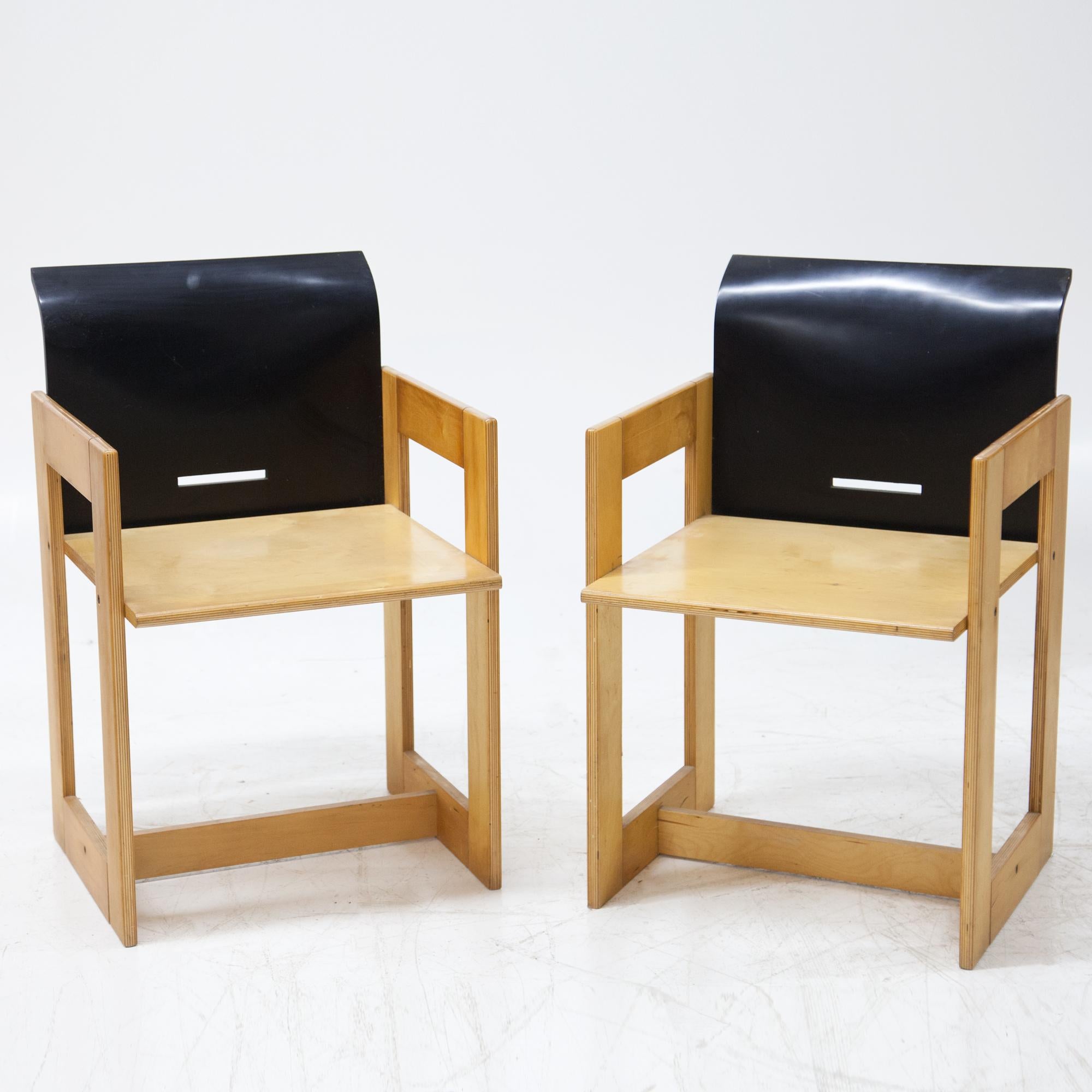 Pair of armchairs in plywood with black lacquered backrests and geometric base.