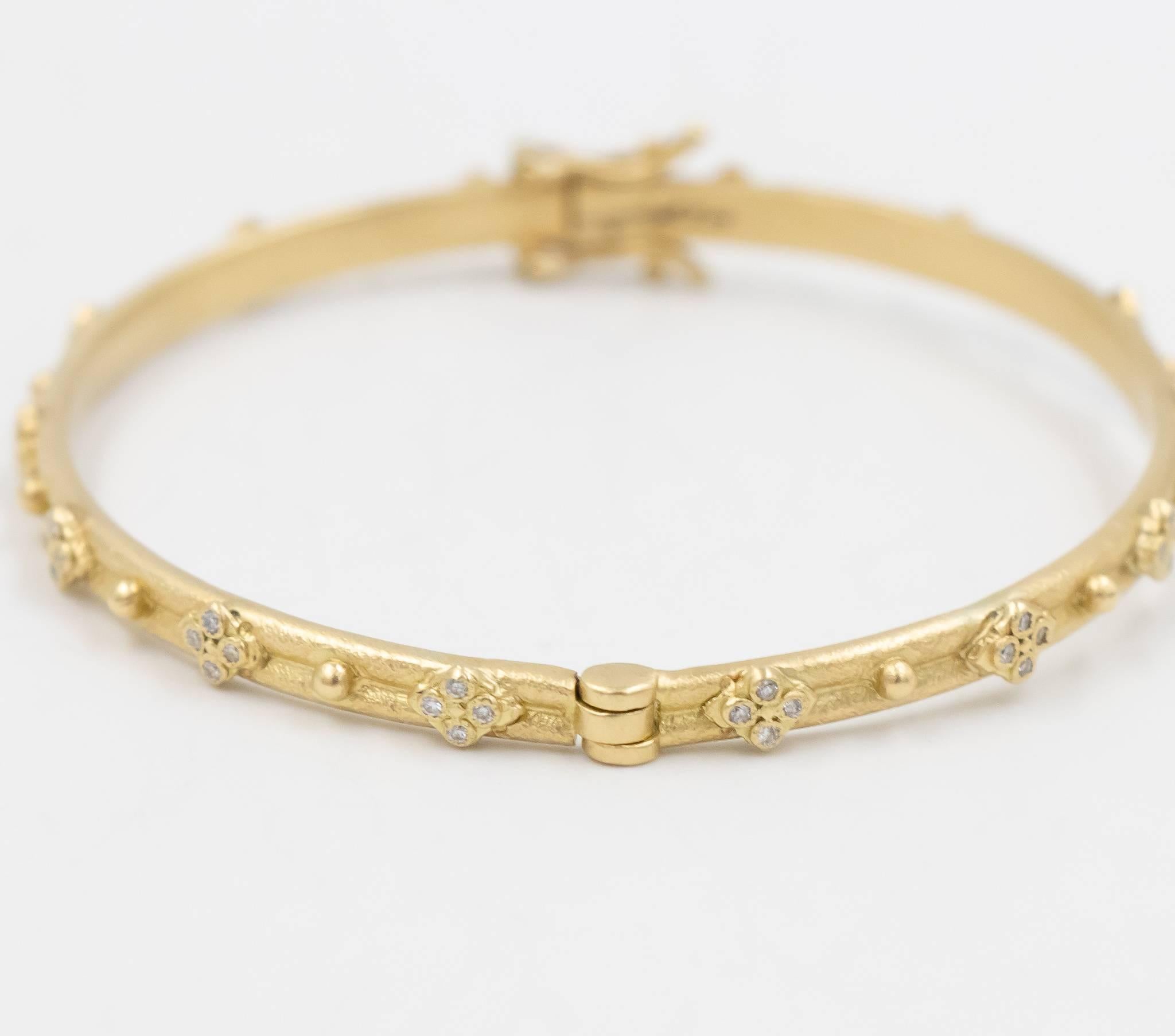 This Armenta huggie bracelet in 18k yellow gold is a Sueno collection piece with white diamonds.  This is a bangle bracelet with a hinge clasp with a security clasp feature.  The diamonds are all set in small stations of four throughout the design. 