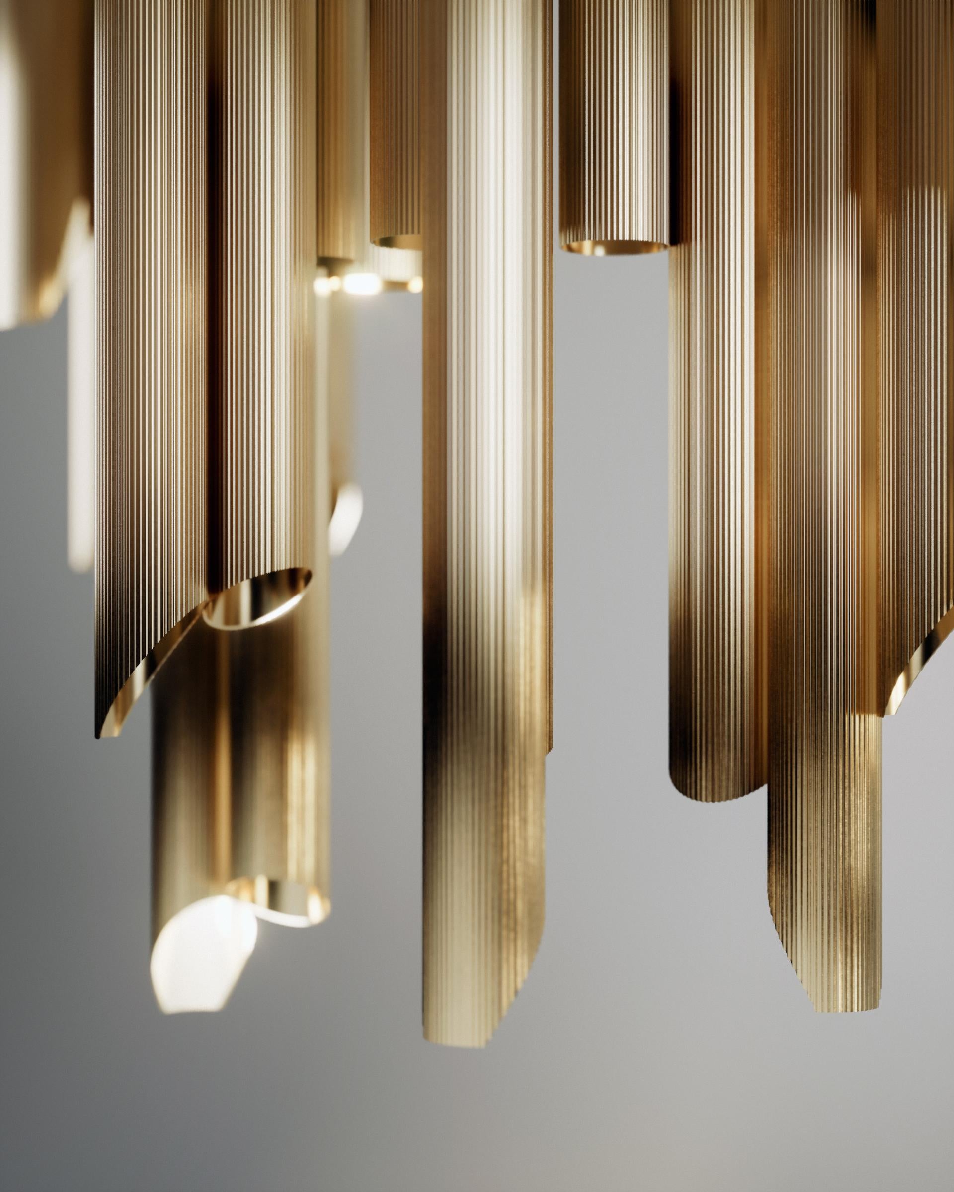 Armilla chandelier by Scattered Disc Objects
Dimensions: D 120 x W 50 x H 50 cm
Material: Brass striped pipes, aluminum, Led spot light, steel cables.

Armilla invites to a relationship with light. The tubes, like Doric columns, call for a