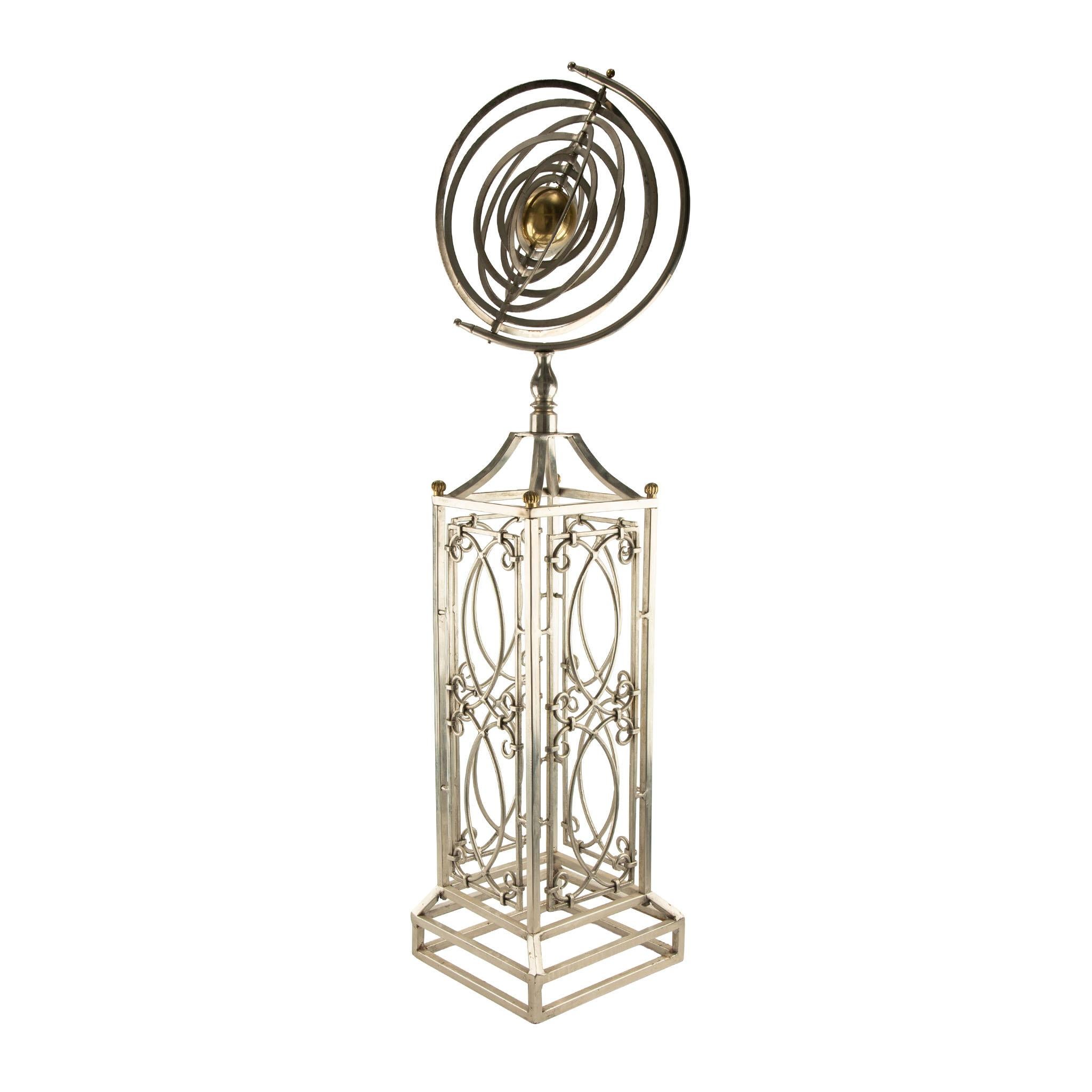  Une élégante sphère armillaire décorative en métal chromé poli avec des accents en laiton, montée sur un socle ajouré au design complexe. La sphère comporte plusieurs anneaux imbriqués représentant l'équateur céleste, les méridiens et les