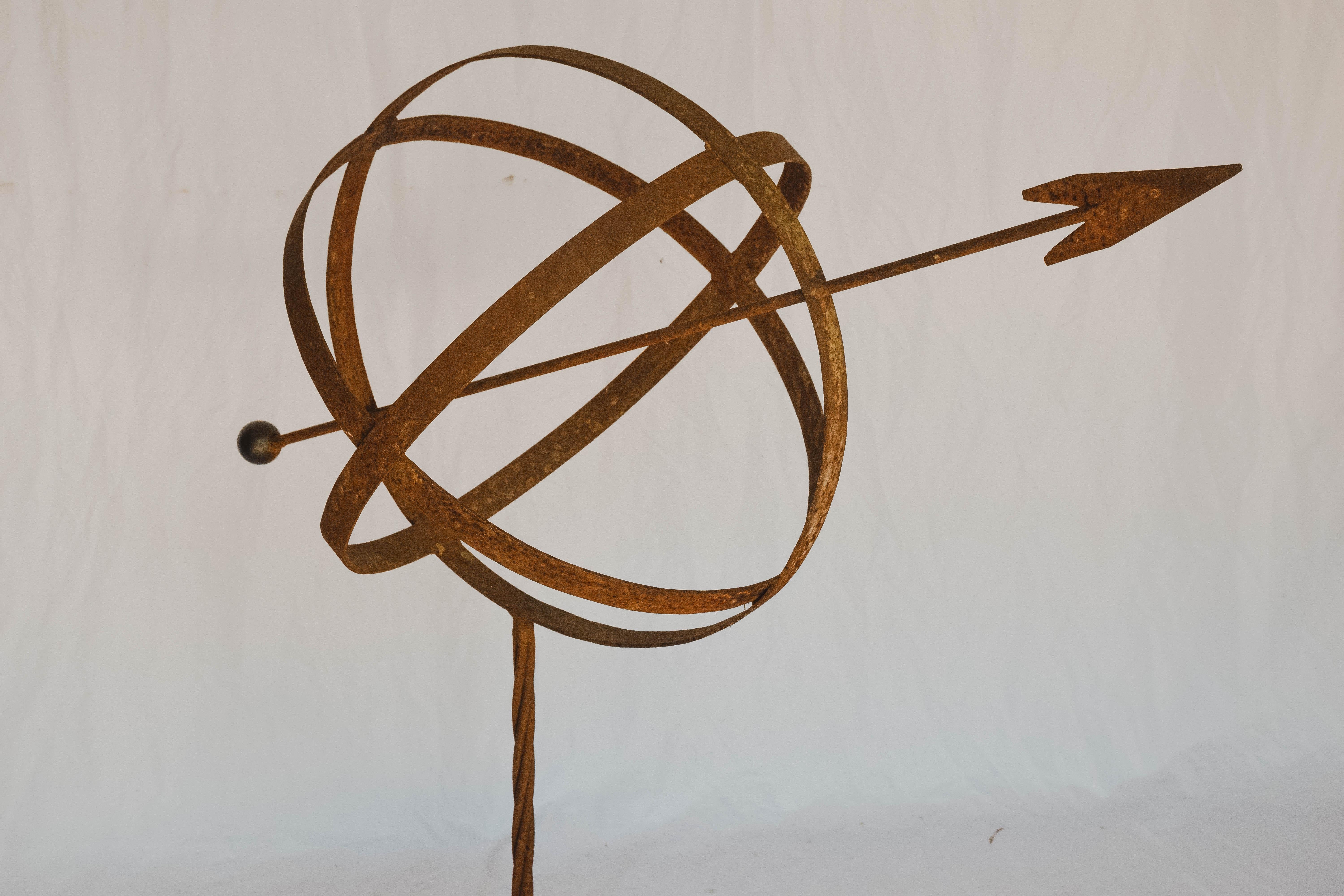 This armillary sphere is made of metal and has a rust color finish. It is mounted on a small concrete square. As a conversation piece or as an addition to a scientific collection, it will add beauty to any environment.