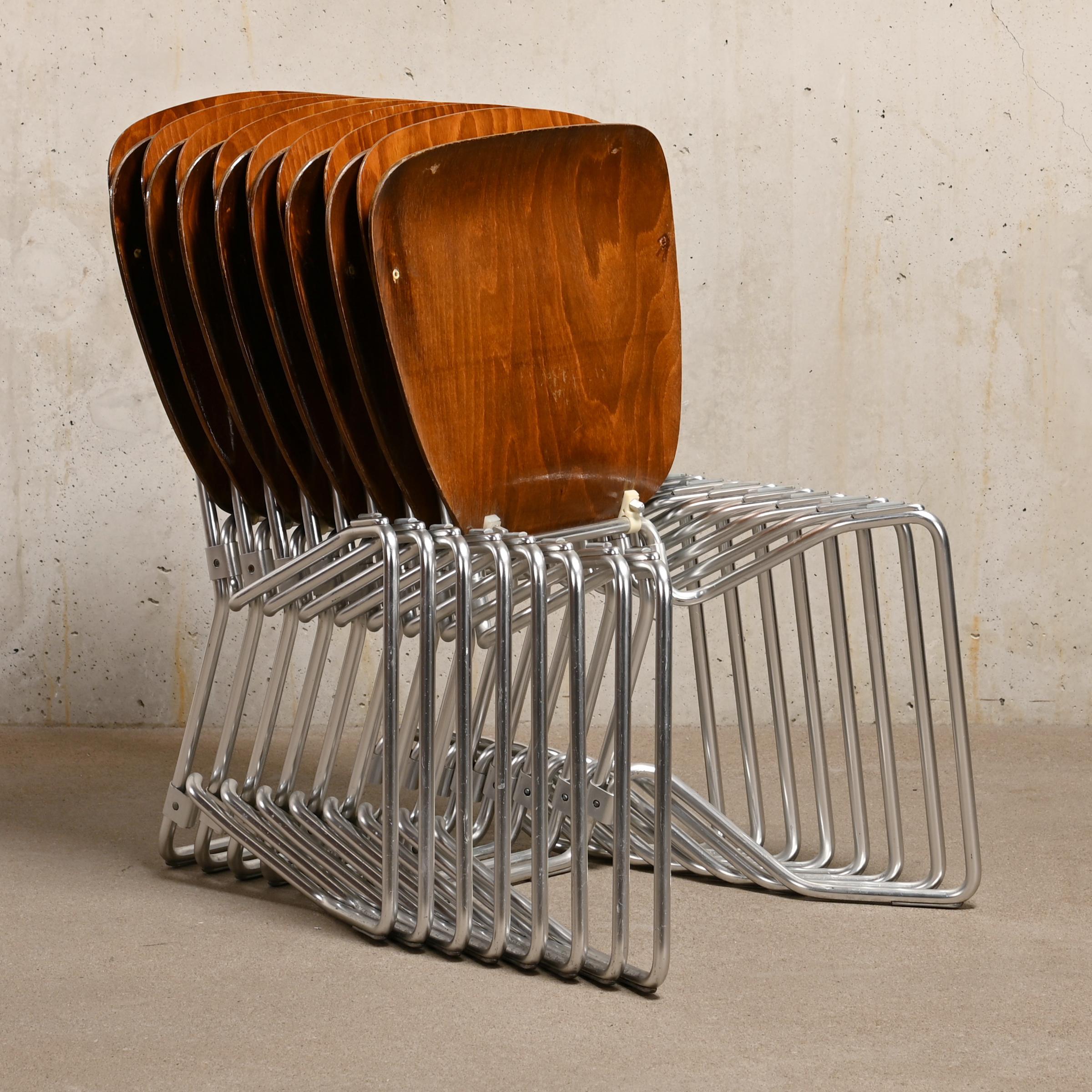 Iconic Aluflex stacking chairs designed by Armin Wirth in 1951 for Philipp Zieringer KG, Switzerland. Very good and thoughtful design for a horizontal stackable chair. Lightweight aluminum frame with dark stained plywood seat and back panel. The