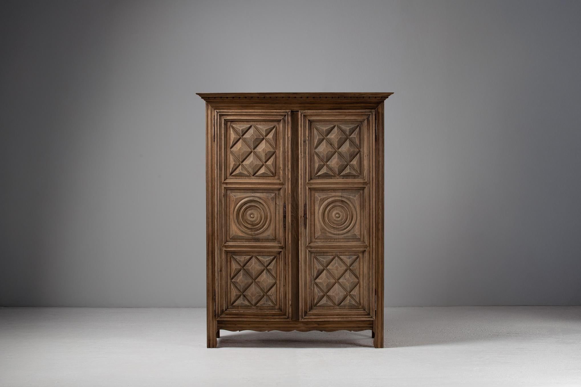 With a façade articulated in rhythmic reliefs, this French armoire engages both light and shadow in a quiet interplay across its surface. Diamond-point panels and concentric rondels lend a sculptural tactility, each carving casting subtle