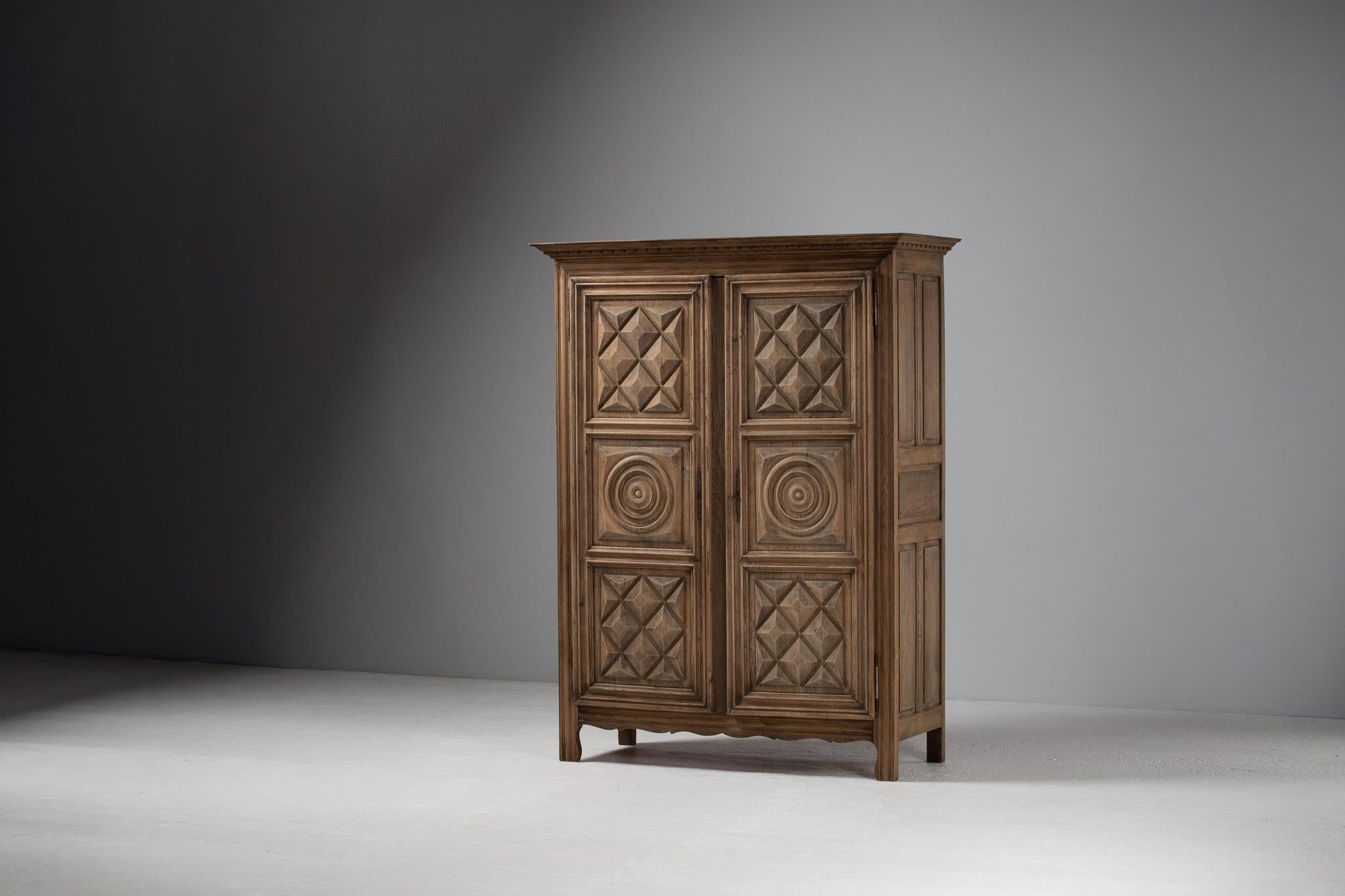 With a façade articulated in rhythmic reliefs, this French armoire engages both light and shadow in a quiet interplay across its surface. Diamond-point panels and concentric rondels lend a sculptural tactility, each carving casting subtle