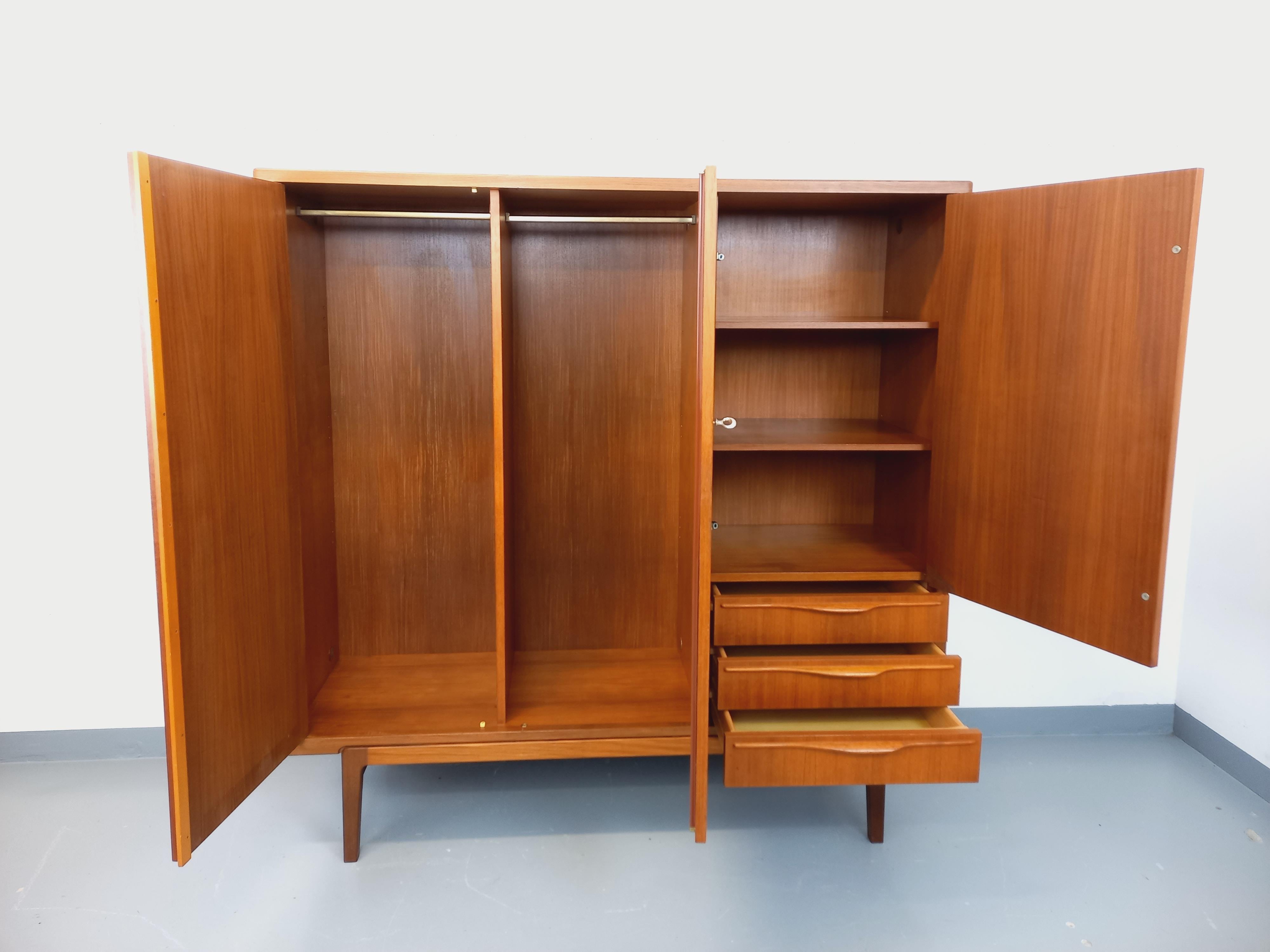 Armoire vintage scandinave des années 60, en teck, attribuée à Carlström & Co pour Möbelfabrik, belles finitions, joli piétement, superbe design des poignées, clé originale. Beaucoup de rangements : 2 portes avec penderies, 1 porte avec étagères