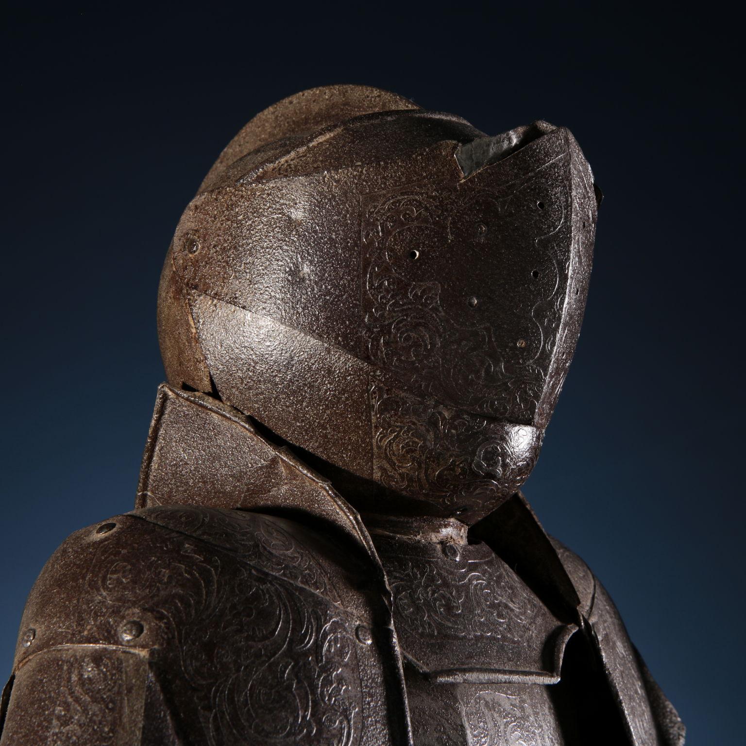 Neo-Renaissance style armor pattern from the late 19th century. All surfaces are engraved with phytomorphic motifs. Rounded helmet with ribbed crest; fan with small circular holes for sight. Crewneck schooner present only in the front blade, shaped
