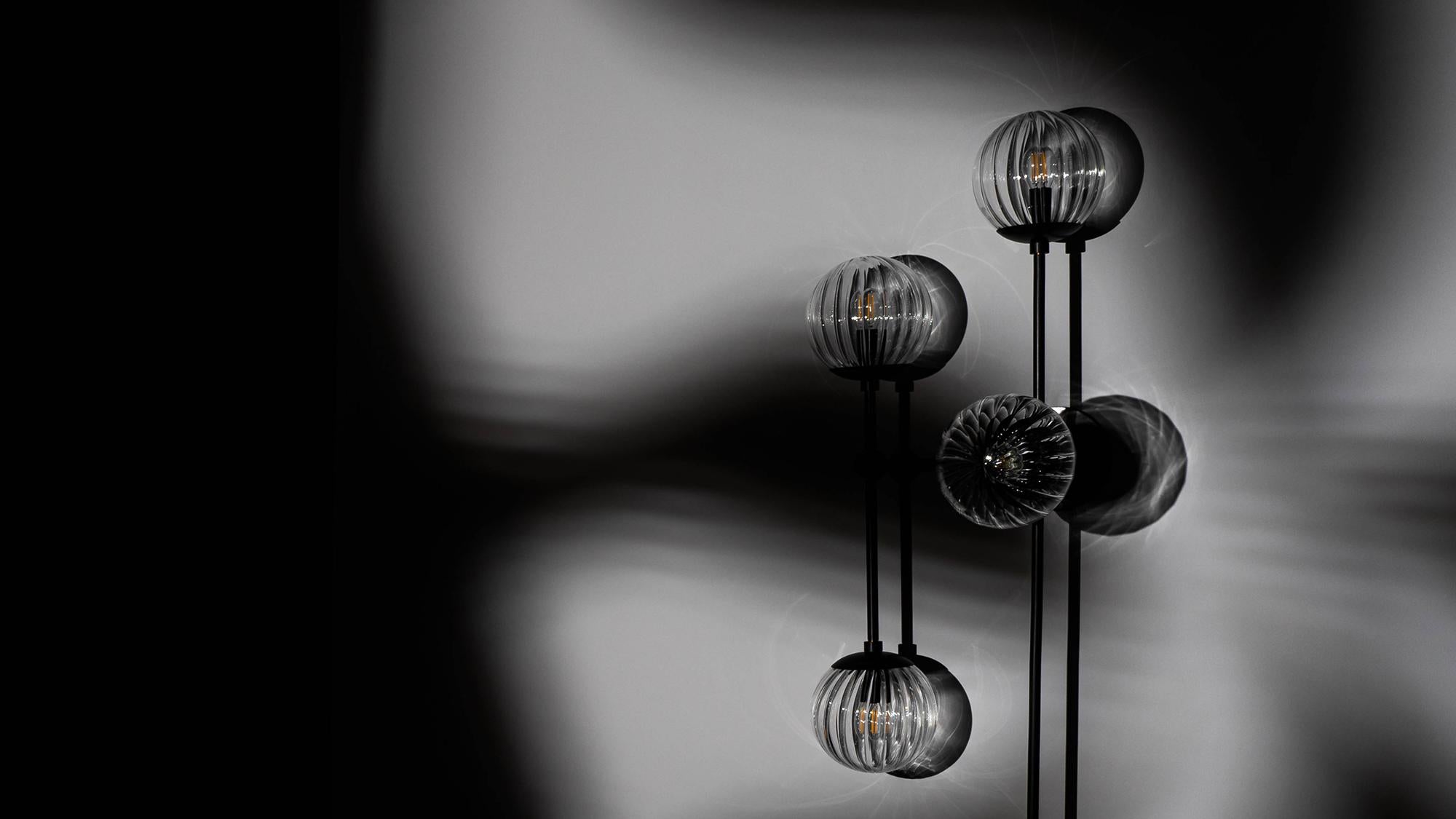 Armstrong 6 captures a sense of movement. Forms connect with spontaneous energy, punctuated by glass spheres. Linear elements complement the carefully crafted brass, echoing a reinforced internal skeleton. The flush mount base gives this lamp
