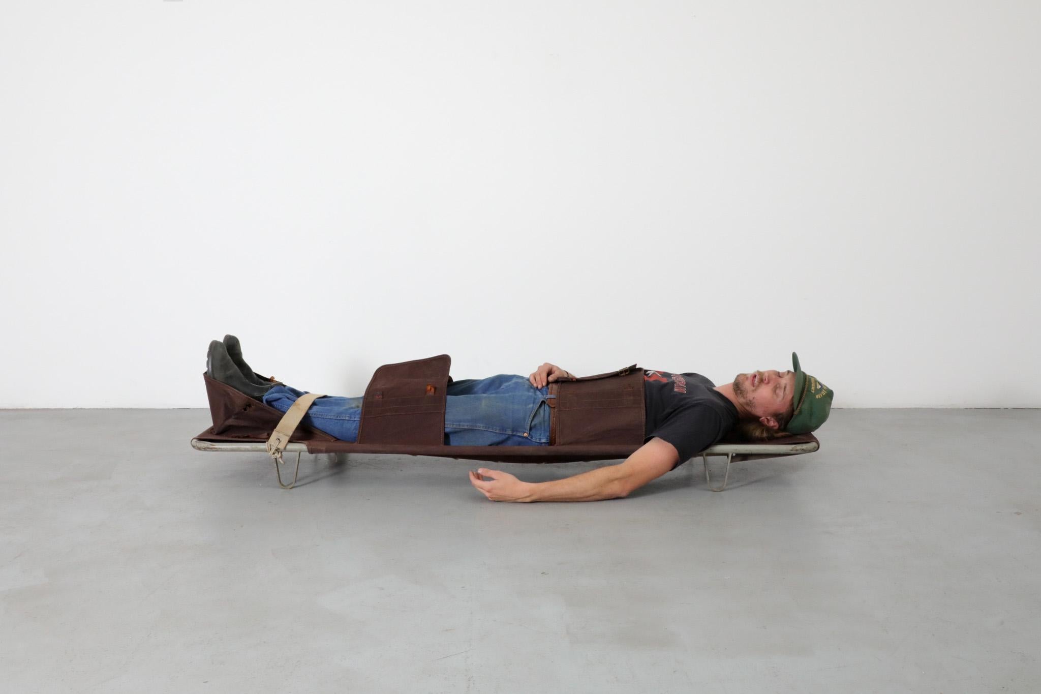 Industrial first aid medic / military gurney / cot / stretcher from the 1950s - 1960s, with tubular metal frame, burgundy canvas, leather, and canvas straps. In original condition, with heavy wear and signs of use, including ripped canvas and