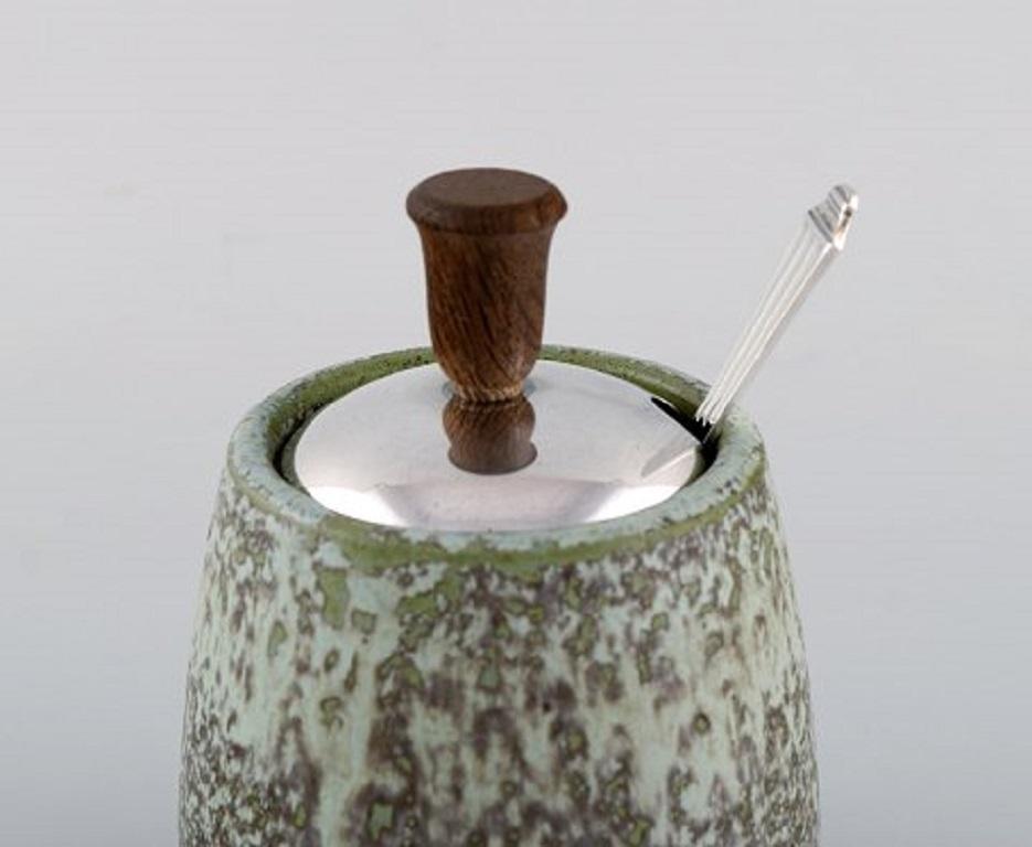 Arne Bang, Denmark. Ceramic marmalade jar with matching silver lid and silver spoon by Hans Hansen. 
Dated 1939.
Measures: 12.5 x 9.5 cm (including lid).
Stamped: AB 18.
Beautiful glaze in green shades.
In very good condition.
  