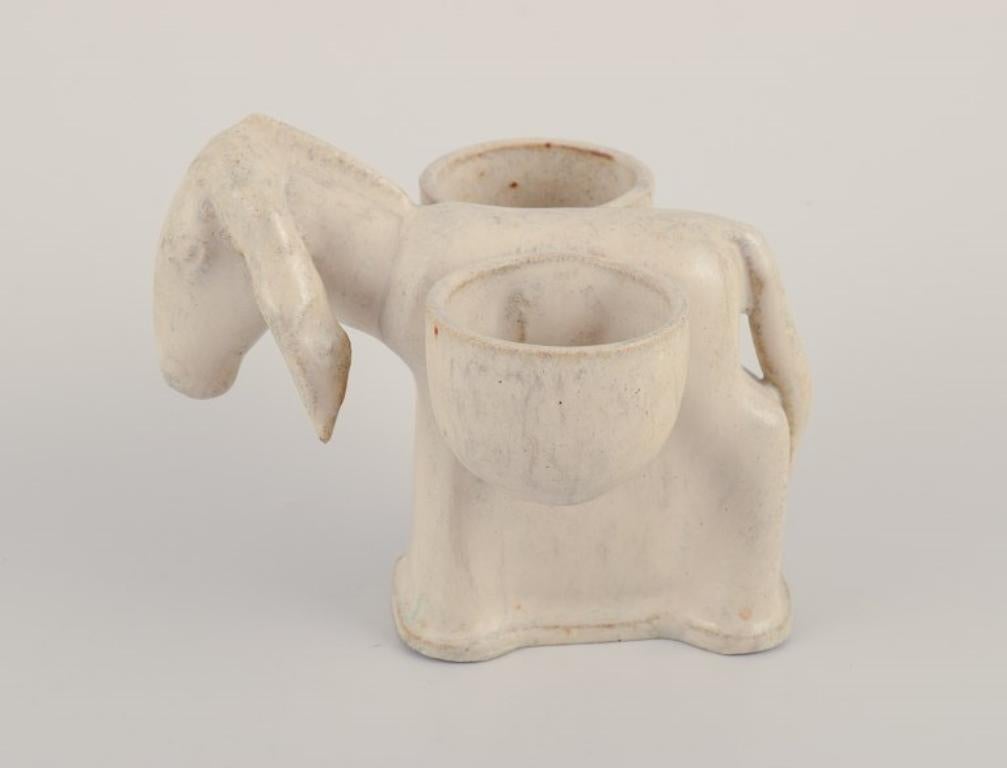 Arne Bang, Danemark. In our own workshop.
Figure d'un âne. Salière.
Glacis dans les tons grisâtres.
Milieu du XXe siècle.
En parfait état.
Signé en monogramme.
Dimensions : L 11,0 cm. x largeur 10,0 cm. x hauteur 8,5 cm : L 11.0 cm. x largeur 10.0