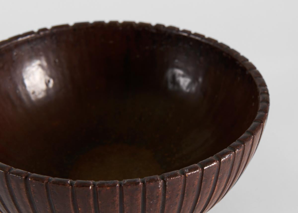 This large bowl is ribbed and richly glazed in a chocolate brown. Signed and numbered 129.