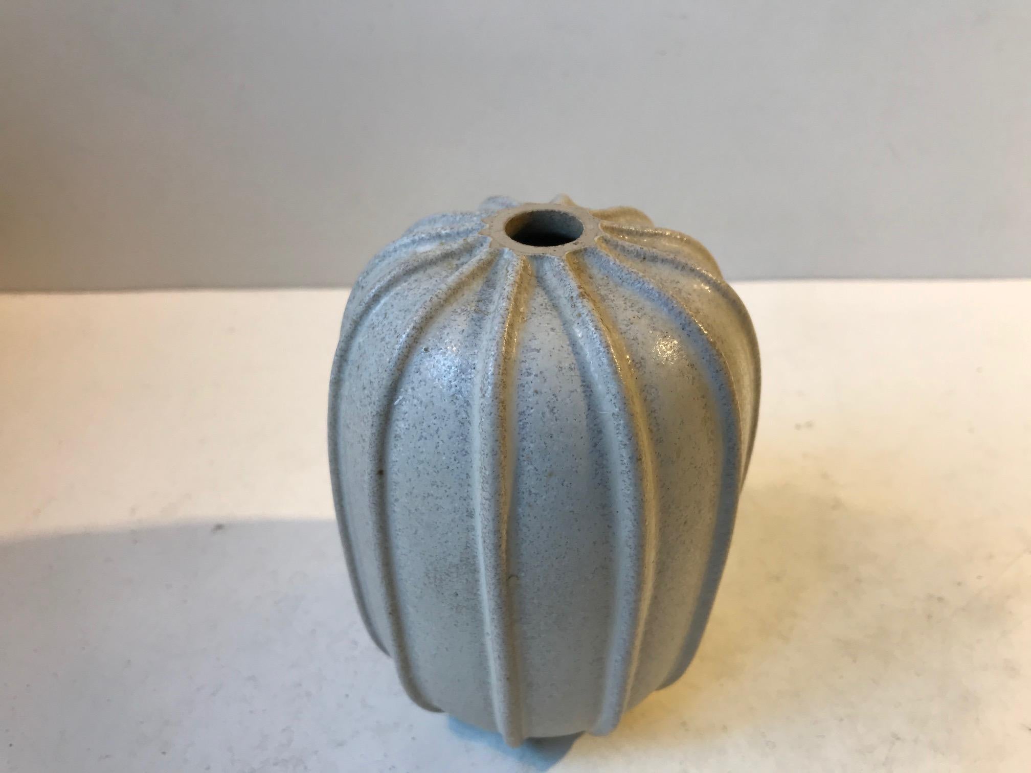 Stoneware vase decorated with vertical ribbings and of-white glaze with specks of blue. Designed by Arne Bang in his own workshop in the latter part of the 1930s. Measurements: H: 12 cm, D: 10 cm. This piece has been restored. Please see the