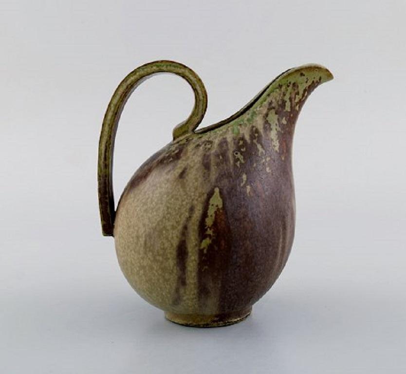 Arne Bang. Jug with handle in glazed ceramics. Model number 161. Beautiful glaze in green and brown shades, 1940s-1950s.
In very good condition.
Signed.
Measures: 15 x 15 cm.