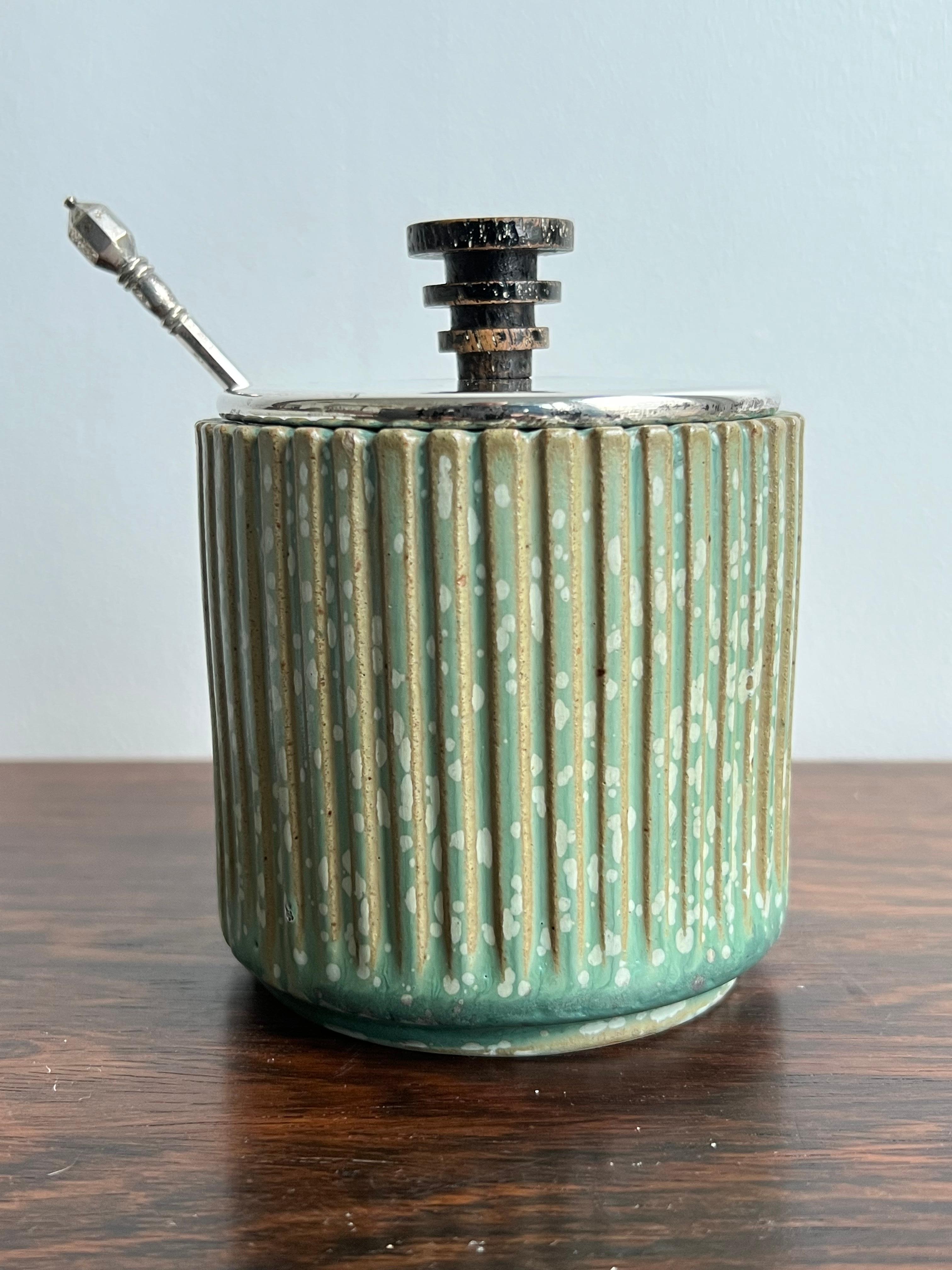 Arne Bang, silver lidded marmelade jar with fine fluted exterior and covered with a charming speckled glaze in tones of green, creme, gray and blues. It carries a silver lid with a handle made of painted (worn) wood and dated 1939, which is also the