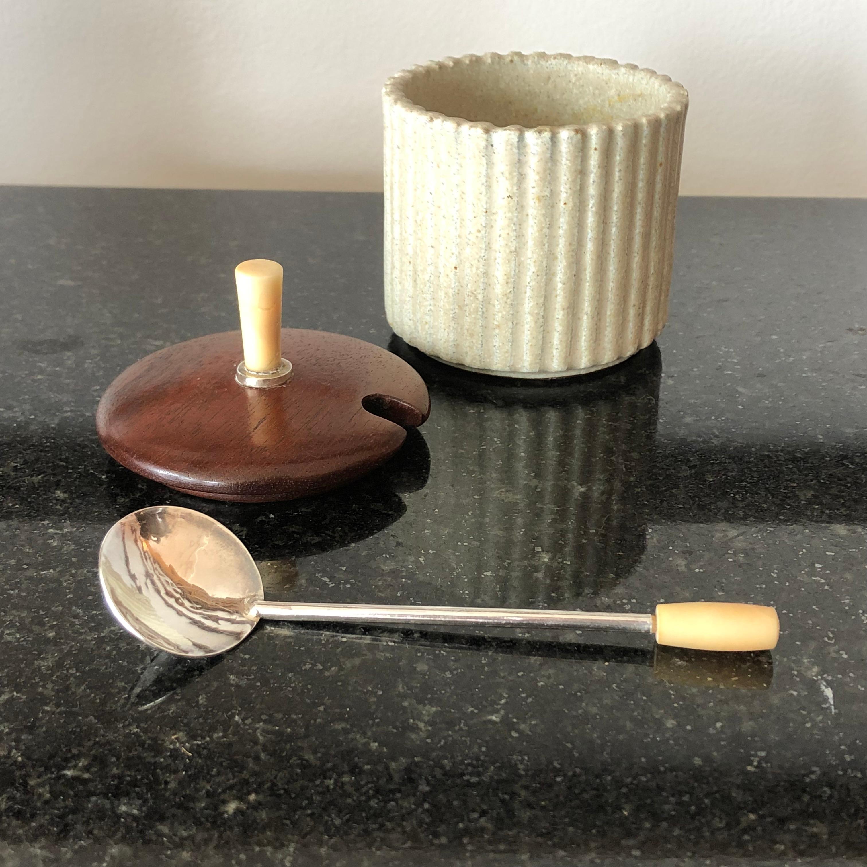 A fine quality Danish art pottery mustard or jam pot by Arne Bang, the reeded beige stoneware base with a teak cover decorated with a silver and bone finial, together with its original handmade sterling silver spoon with bone handle. Signed and
