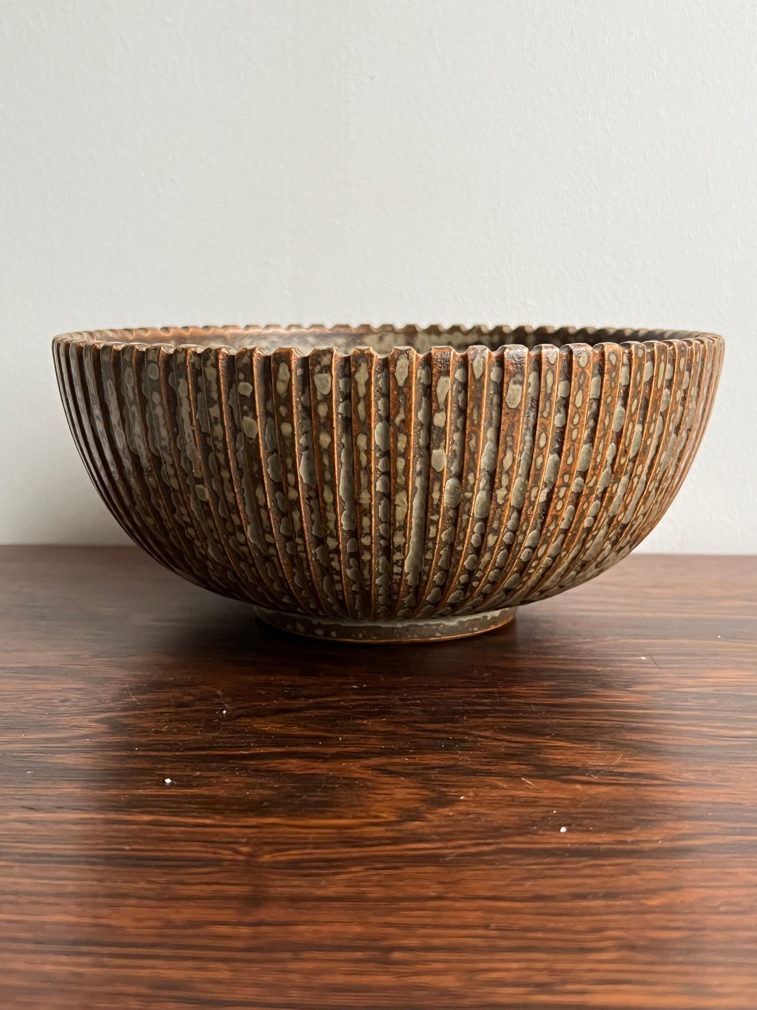 Arne Bang, bowl, own studio, Denmark 1930’s. The fluted exterior and the strictly geometric shape makes tis bowl very decorative in any interior. At the same time, it carries a speckled glaze in various shades of browns and creme. It has a few