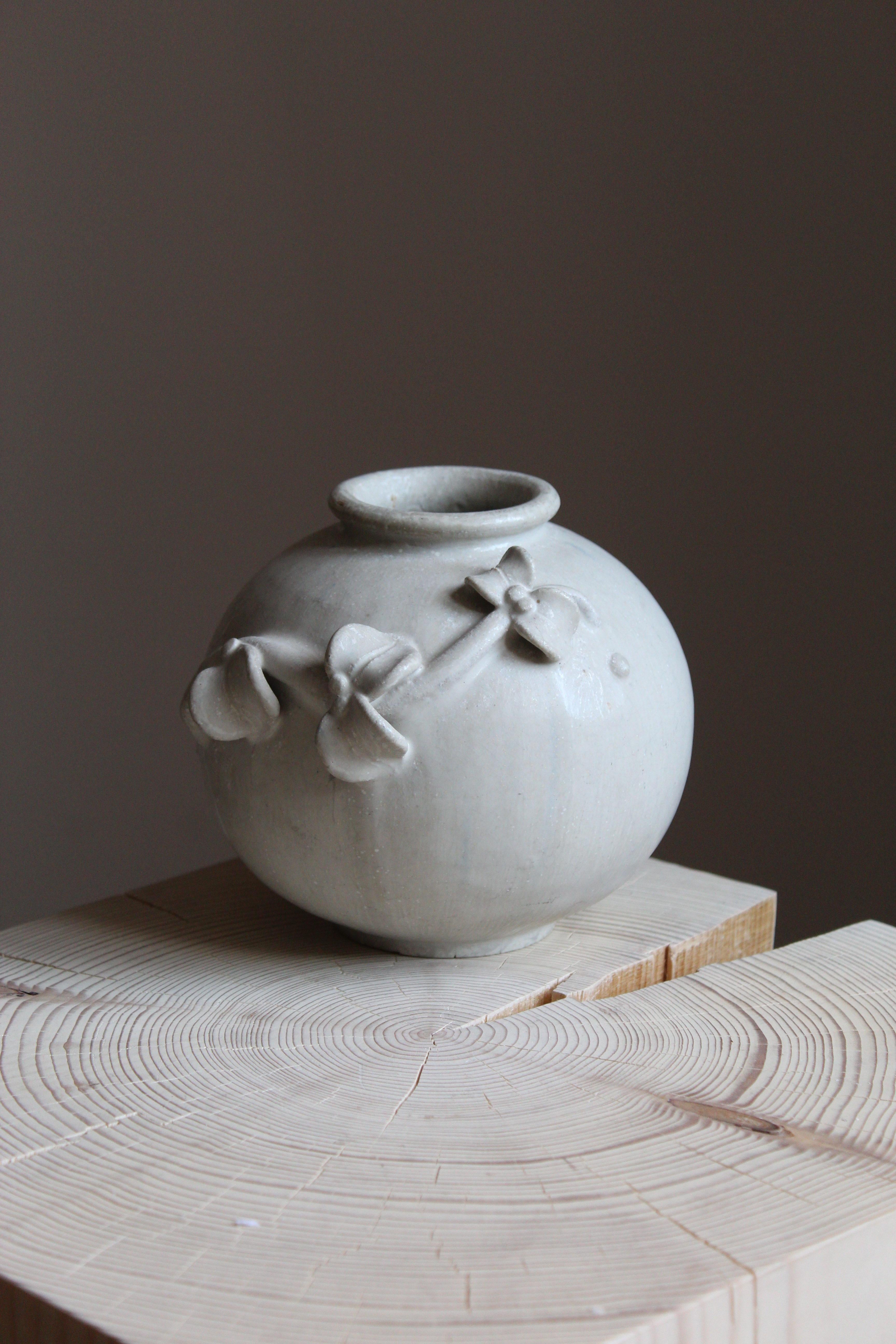 An early vase. Designed by Arne Bang, produced c. 1927. Light-grey glazed stoneware. Features ornamental floral motifs, typical to Bangs production.

Other designers of the period include Axel Salto, Wilhelm Kåge, Gunnar Nylund, Berndt Friberg,