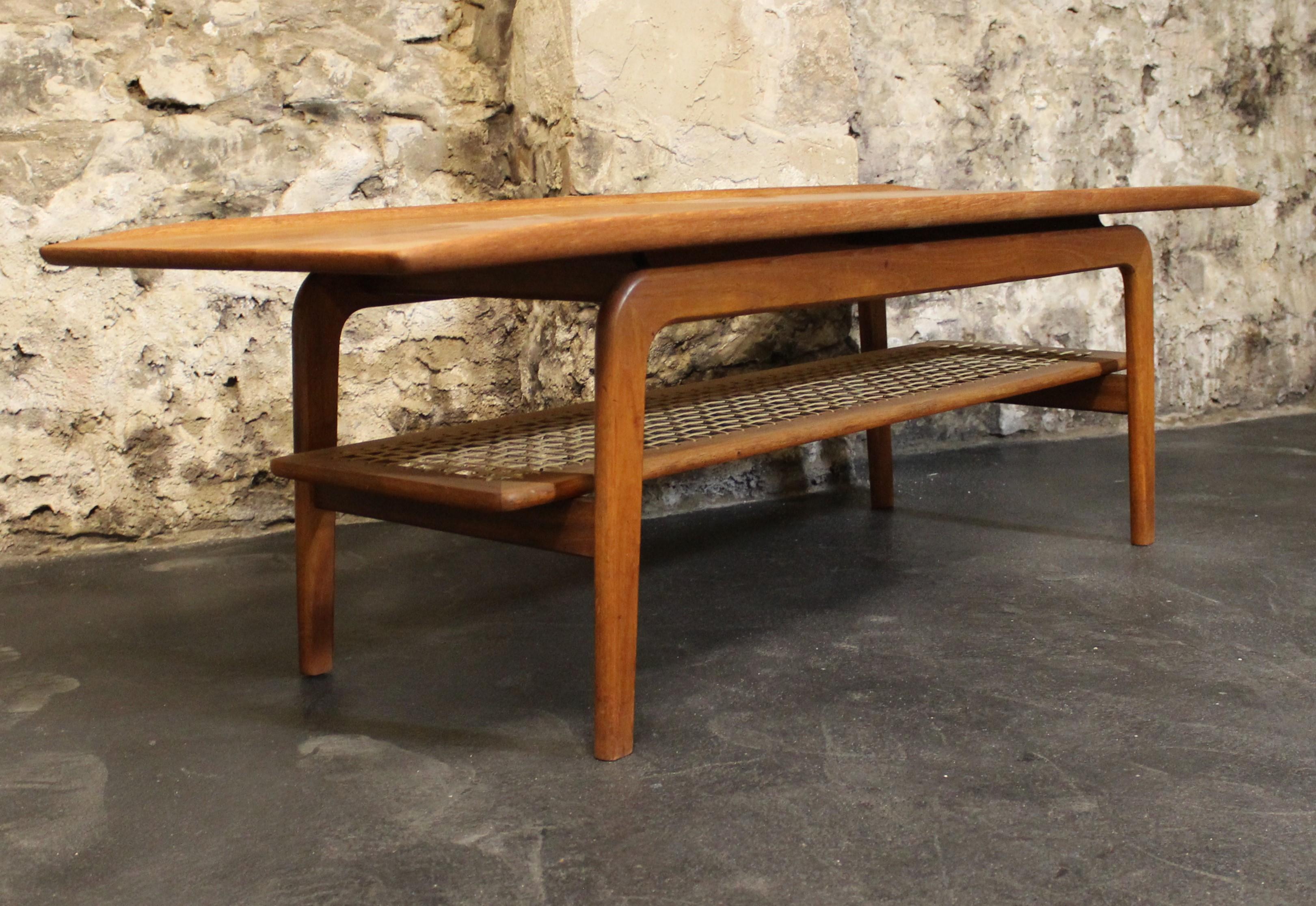 Stunning midcentury Danish teak coffee table with magazine rack designed by Arne Hovmand Olsen.

Superb raised edges and top designed to appear to be floating being raised from the frame with metal supports. Stunning curved frame and looks