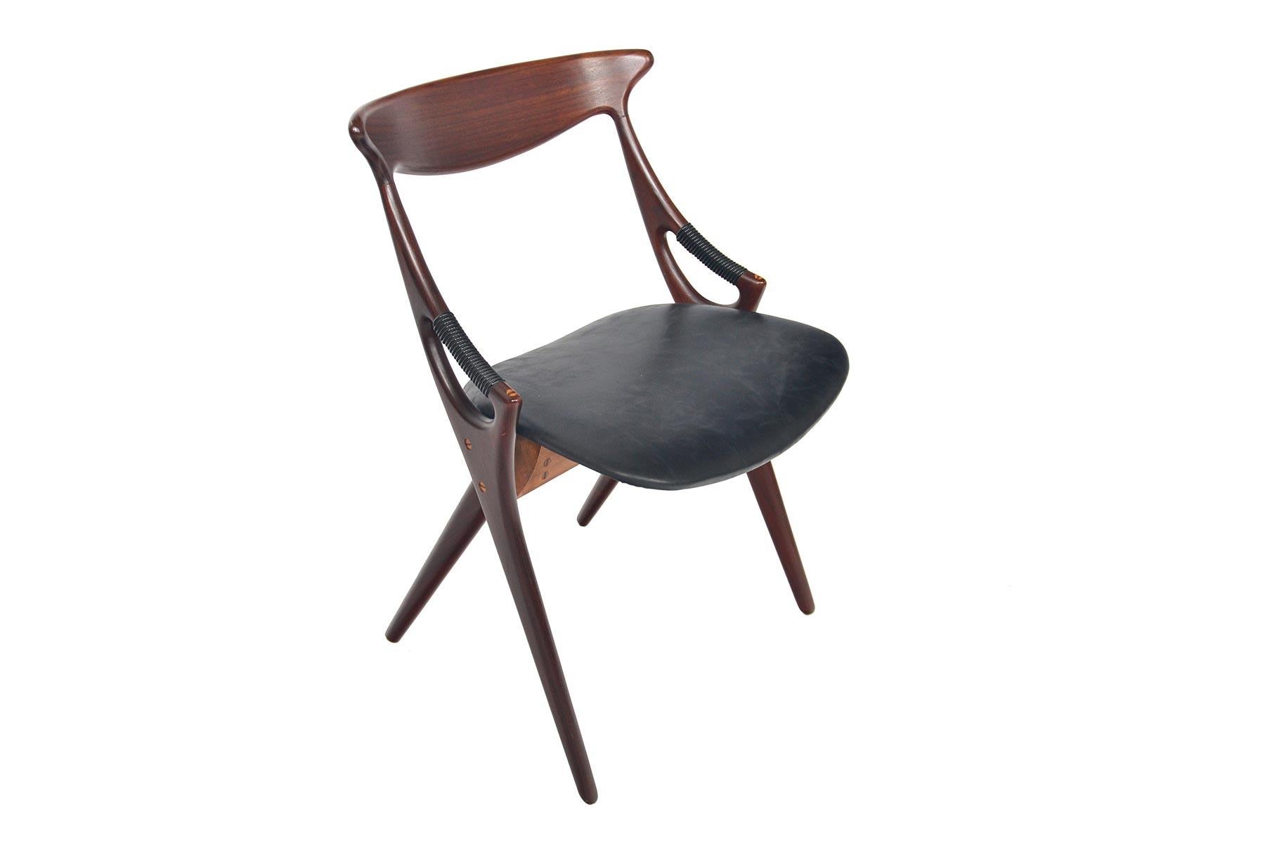 This stunning Danish modern dining chair was designed by Arne Hovmand Olsen for Mogens Kold in 1959 as model 71. Beautifully sculpted, the frame offers continuous joinery extending from the backrest to the scissored leg design. Plastic wrapped