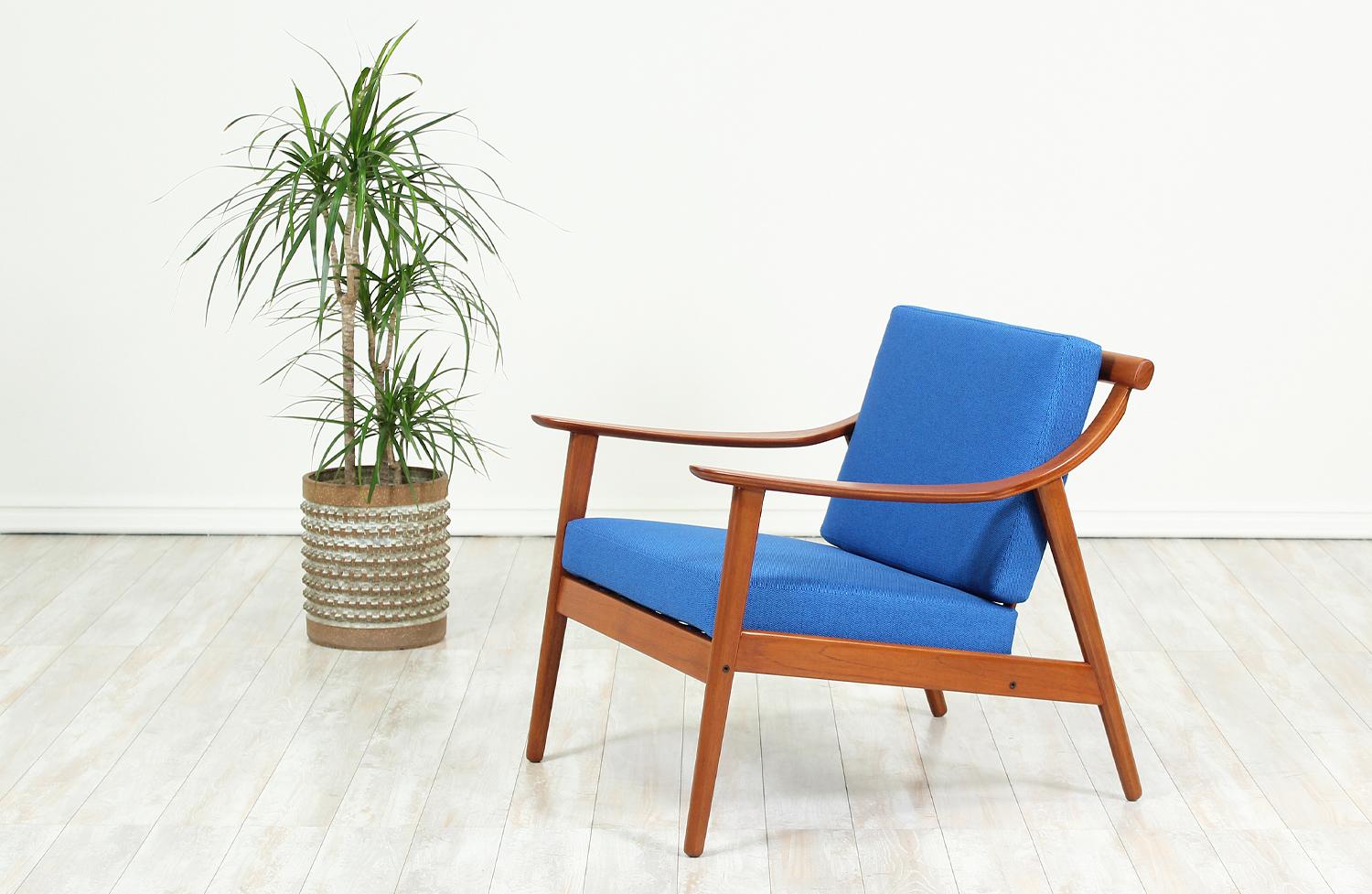 Beautifully crafted lounge chair designed by Arne Hovmand-Olsen for Mogens Kold in Denmark, circa 1950s. This Danish Modern chair features a solid teak wood frame with a slatted back and swooping bentwood armrests. The back and seat cushions are new