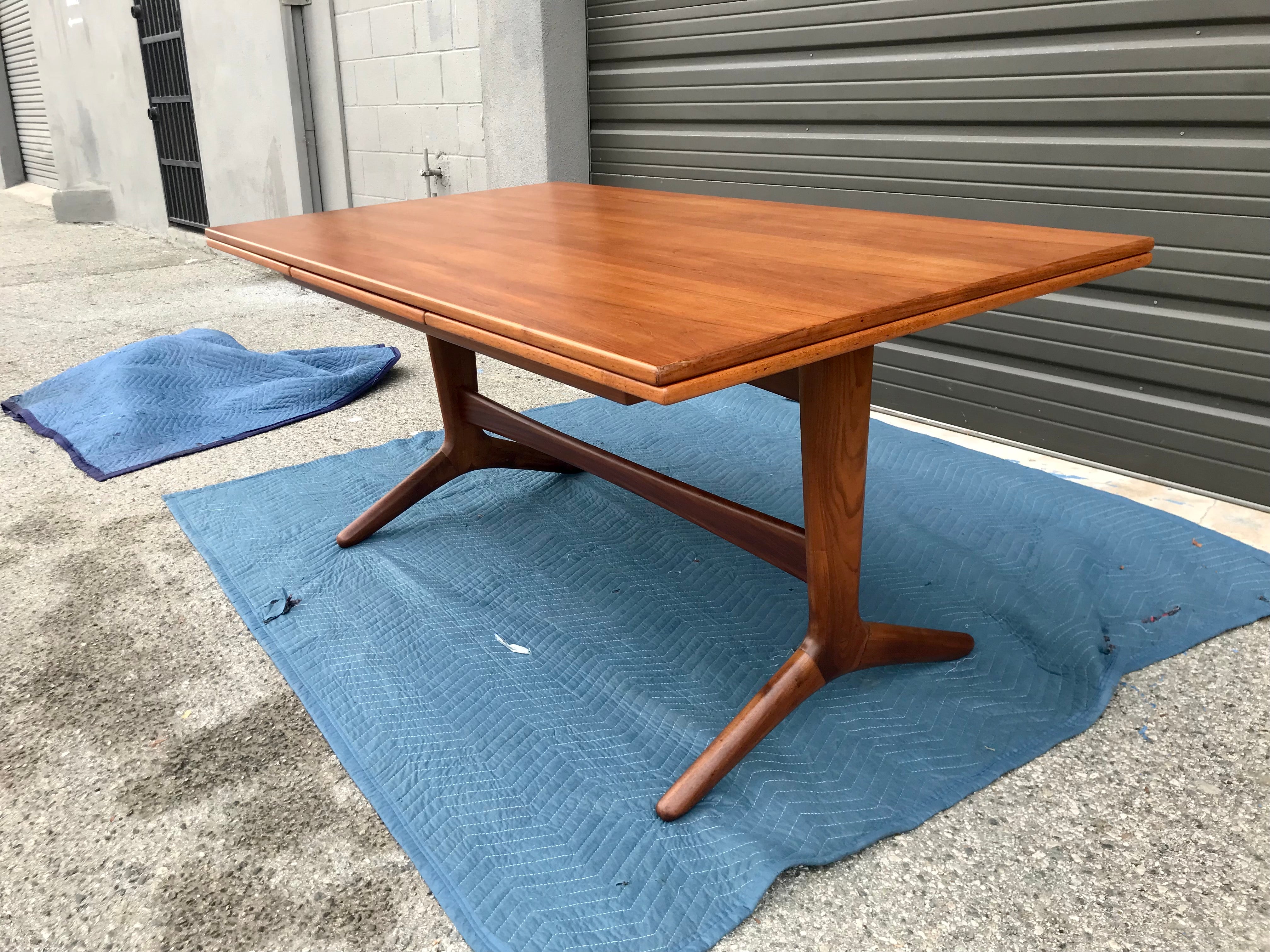 Classic Danish modern design table top with unique sculpted base.
The legs are sort of a fish / whale tail style form.
Two extendable leaves. 
The legs, support rails and base top frame are solid teak wood, the table top and leaves are teak