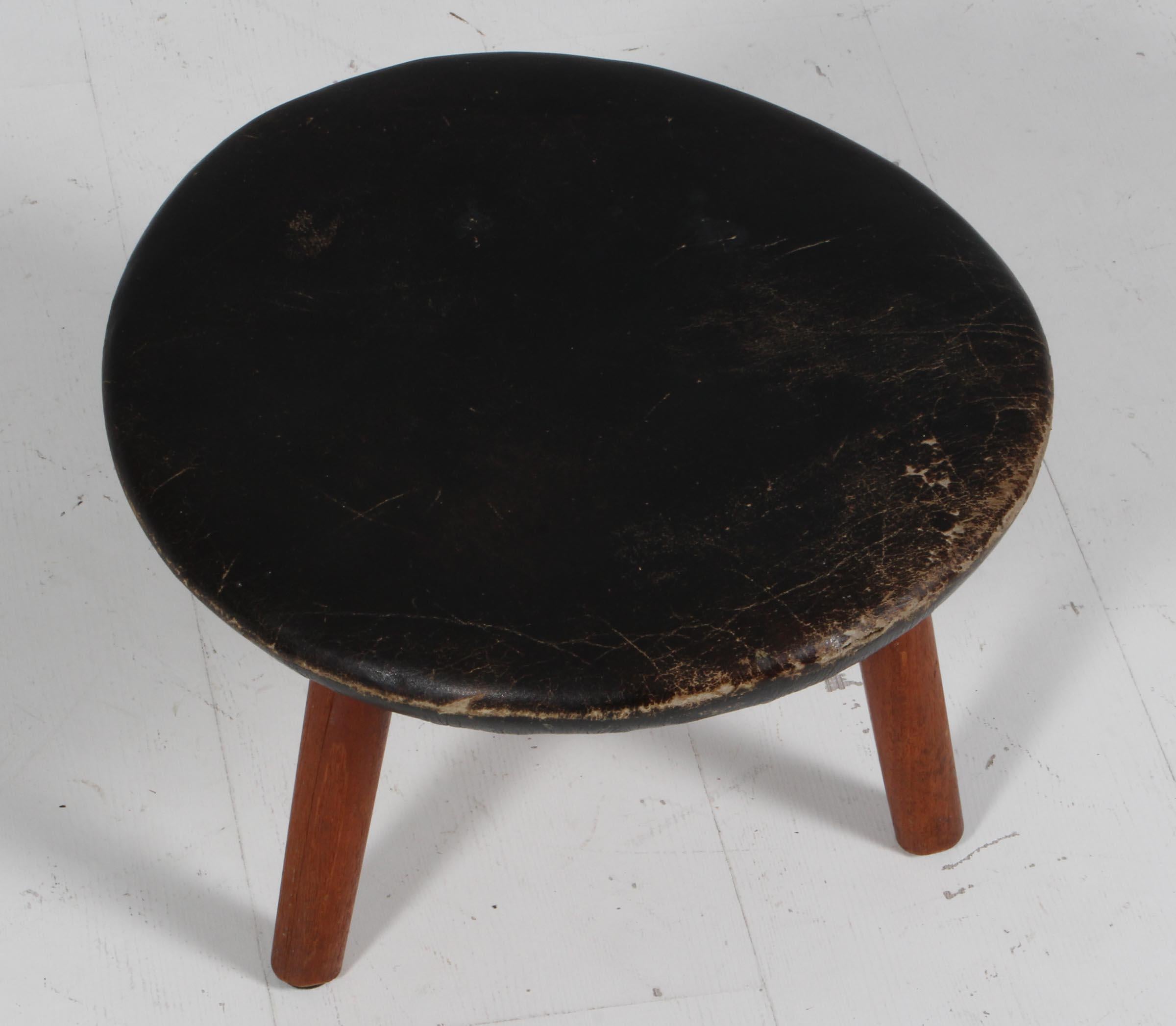 Pouf Arne Hovmand-Olsen in pelle patinata.

Gambe in teak massiccio.

Realizzato da Kolds Savværk.