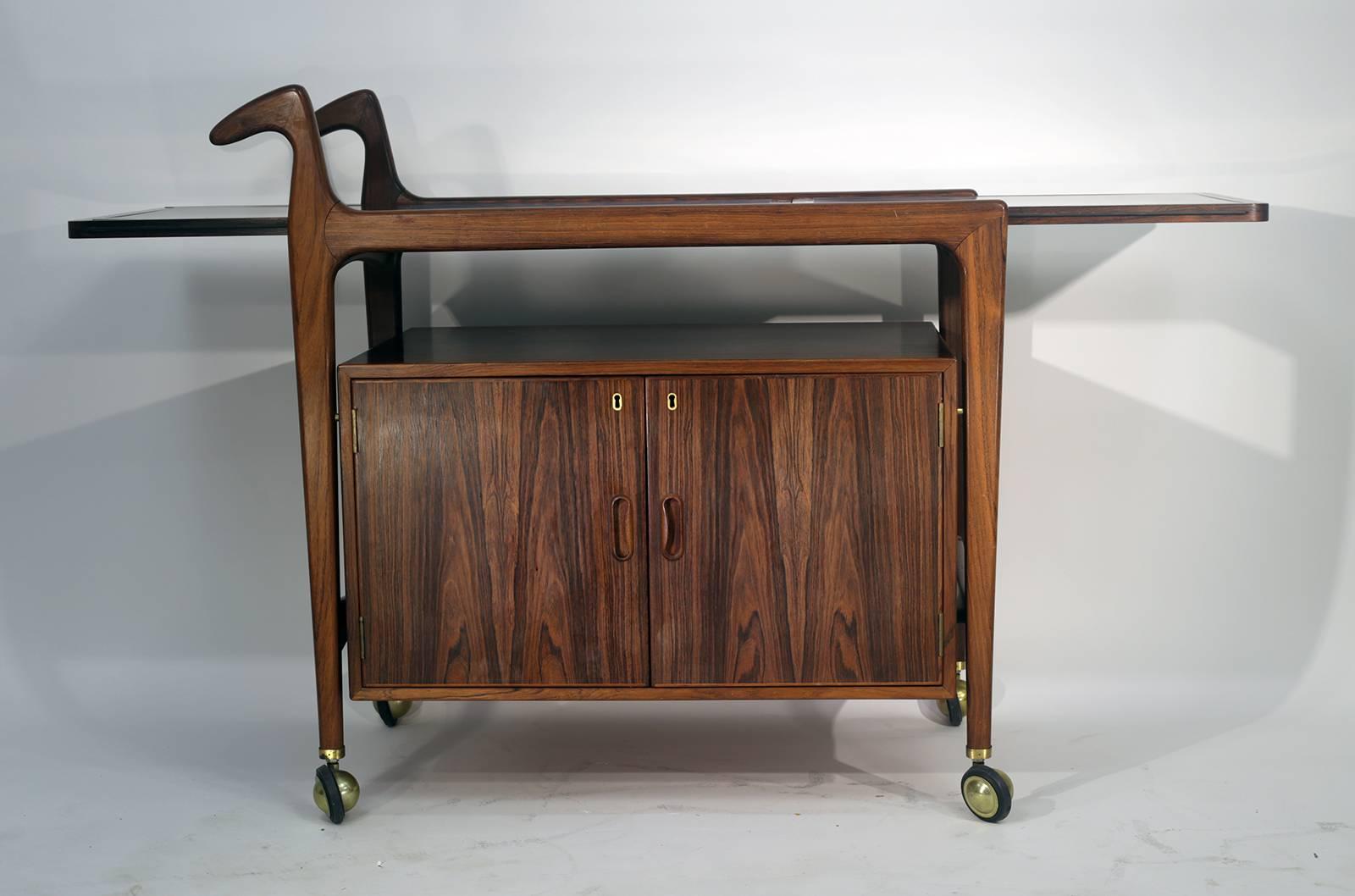 Handsome sculptural rosewood bar cart black laminate inset top with drop-leaf on wheels.