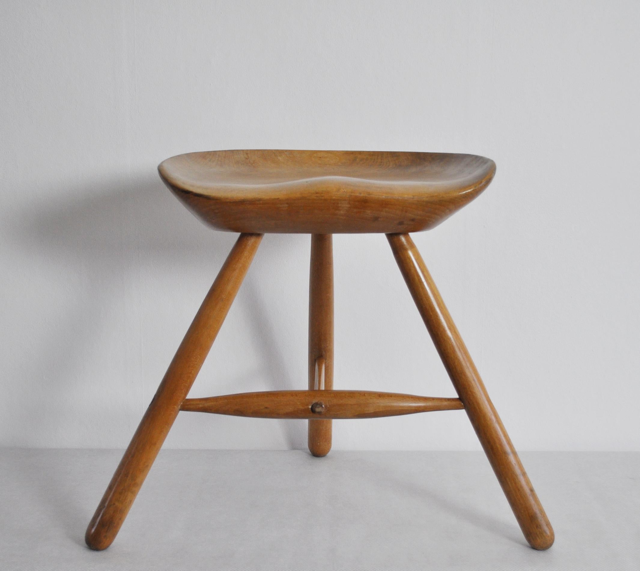 This recognizable stool was designed by Arne Hovmand-Olsen in Denmark, circa 1950. It has three dispersed solid beech legs with a hand carved sculptural solid beech seat. Very fine craftsmanship.
It has a warm brown wooden color with patination