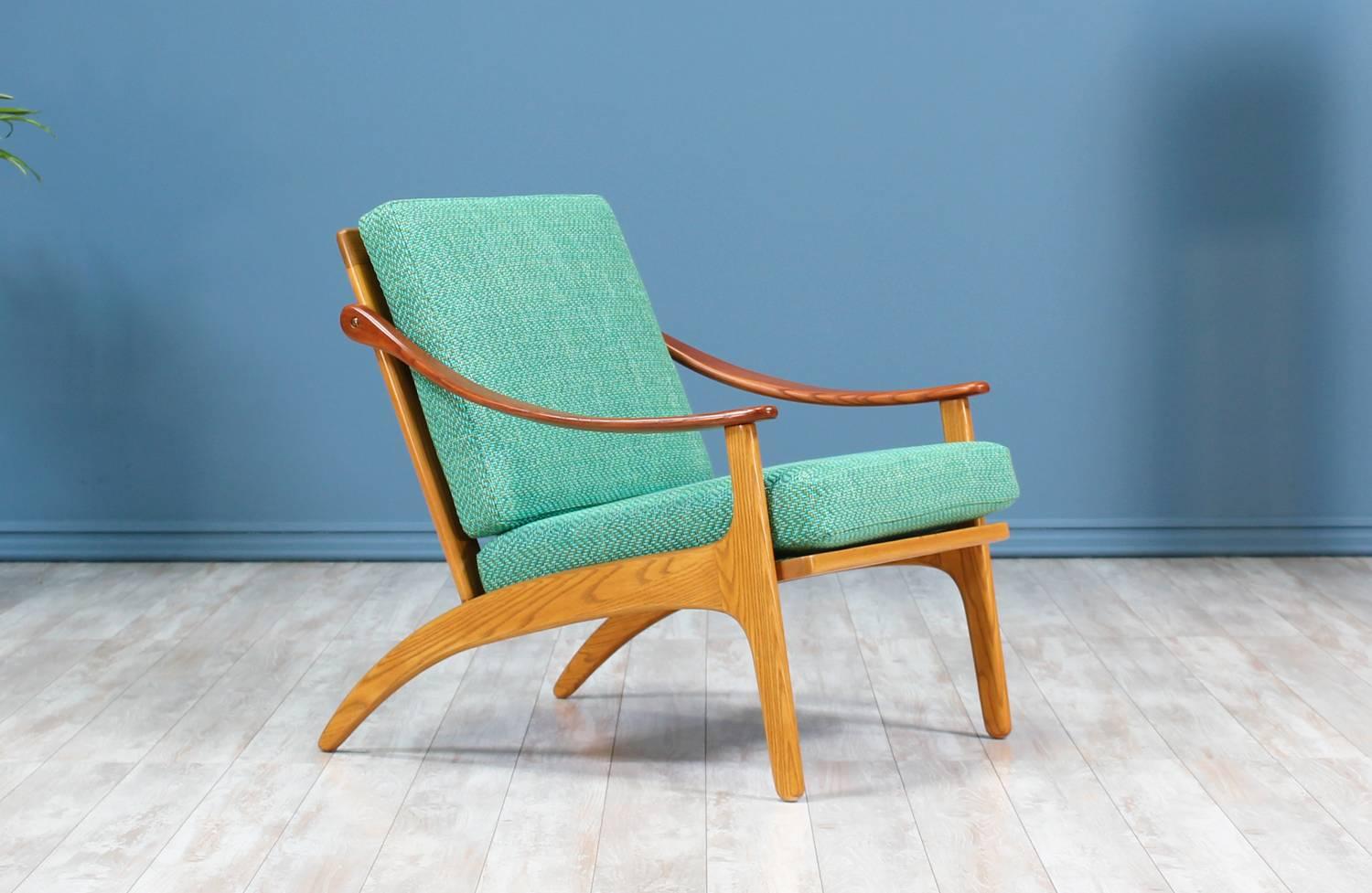Lounge chair designed by Danish furniture designer, Arne Hovmand-Olsen, for Mogens Kold in Denmark circa 1950’s. Featuring an oak wood frame with teak accents including the curvilinear arm rests and the five vertical spindles adorning the back.