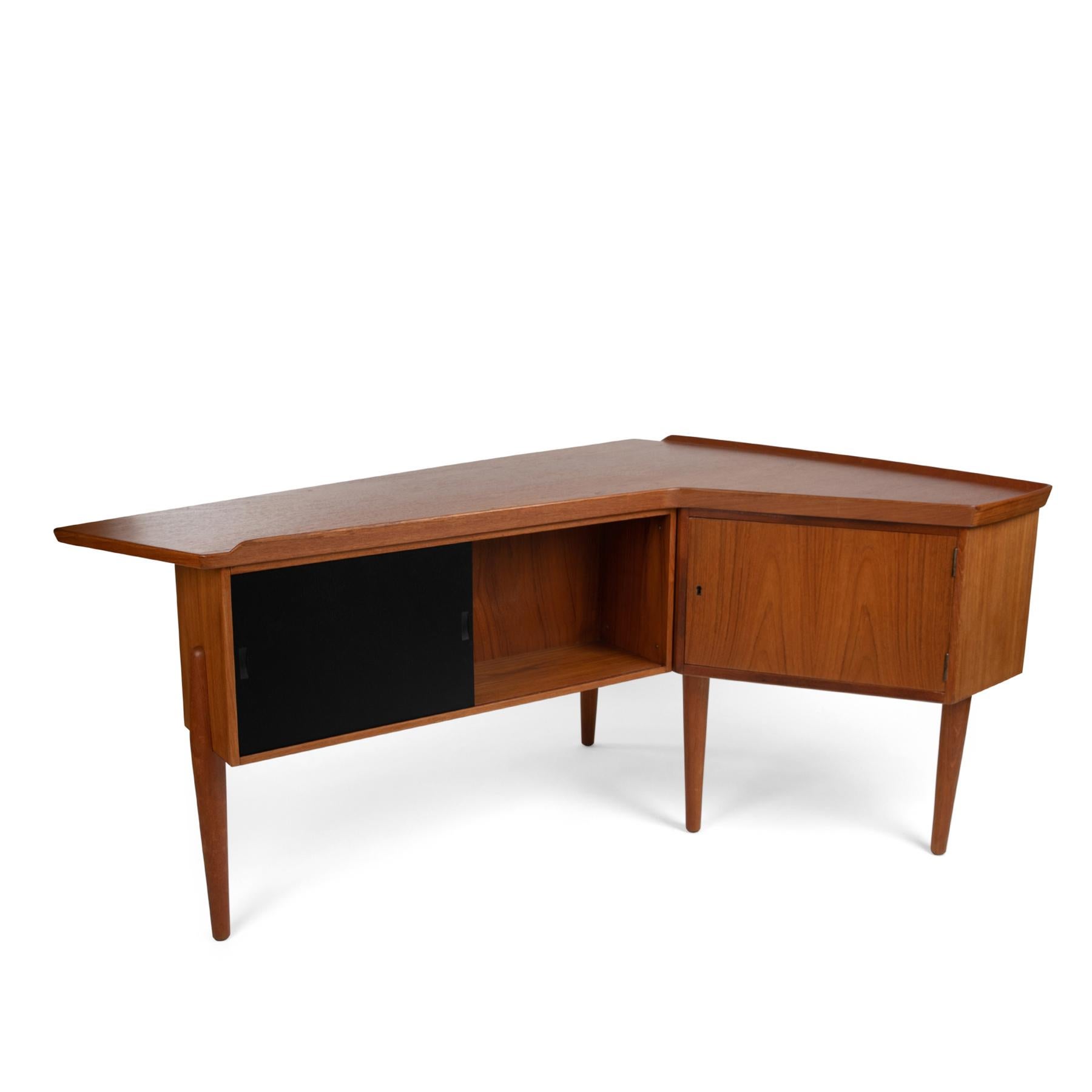 Arne Hovmand-Olsen teak, brass and lacquered desk, circa early 1960s. This sculptural example has three drawers with inset round teak pulls on the front, sliding ebonized door and additional storage on the back. The unusual boomerang form lends