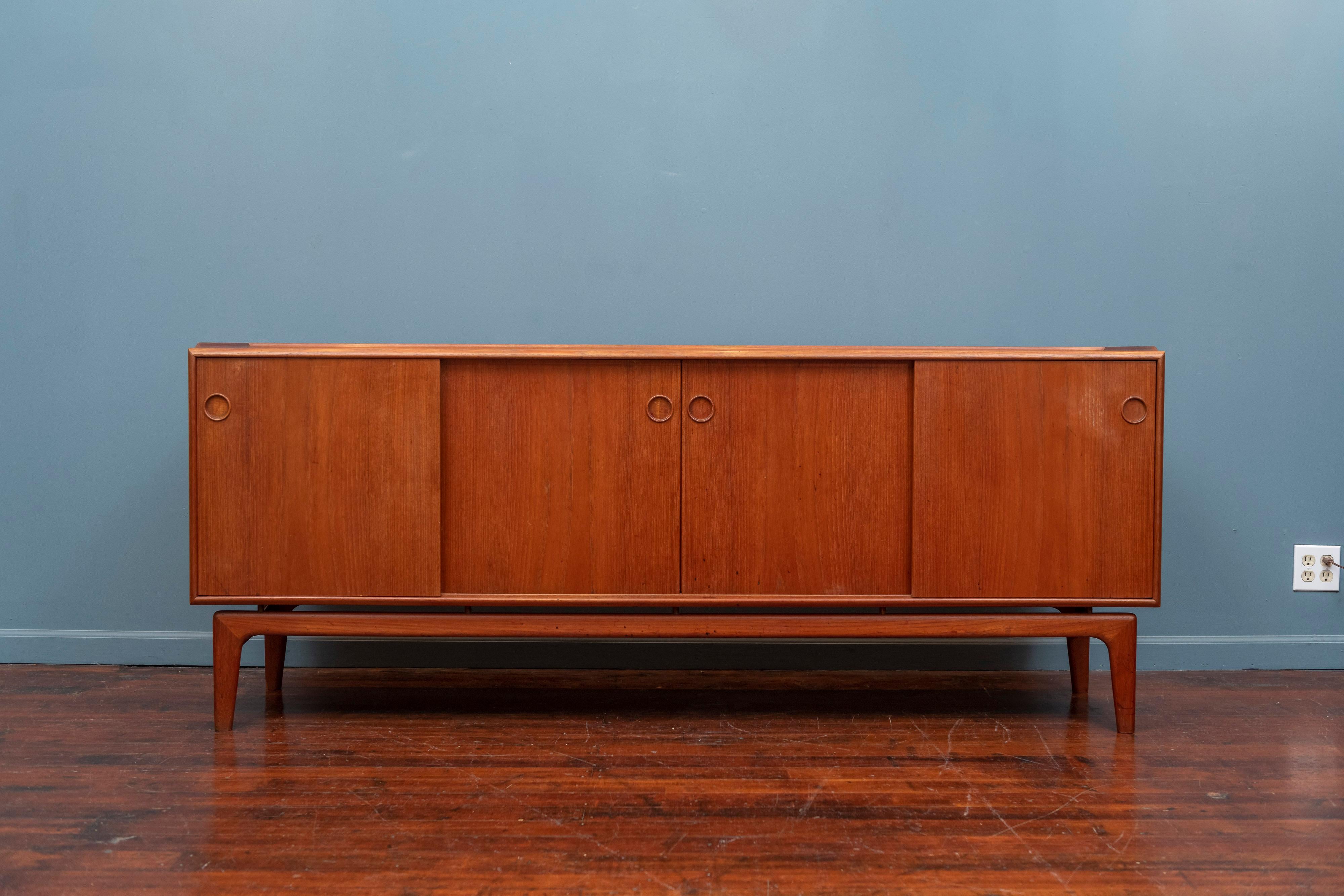 Arne Hovmand Olsen design teak credenza, Denmark. Sculpted lip to the top on a floating base with four sliding doors that operate smoothly concealing five drawers and three interior shelves.
In very good original condition with a chip to rear left