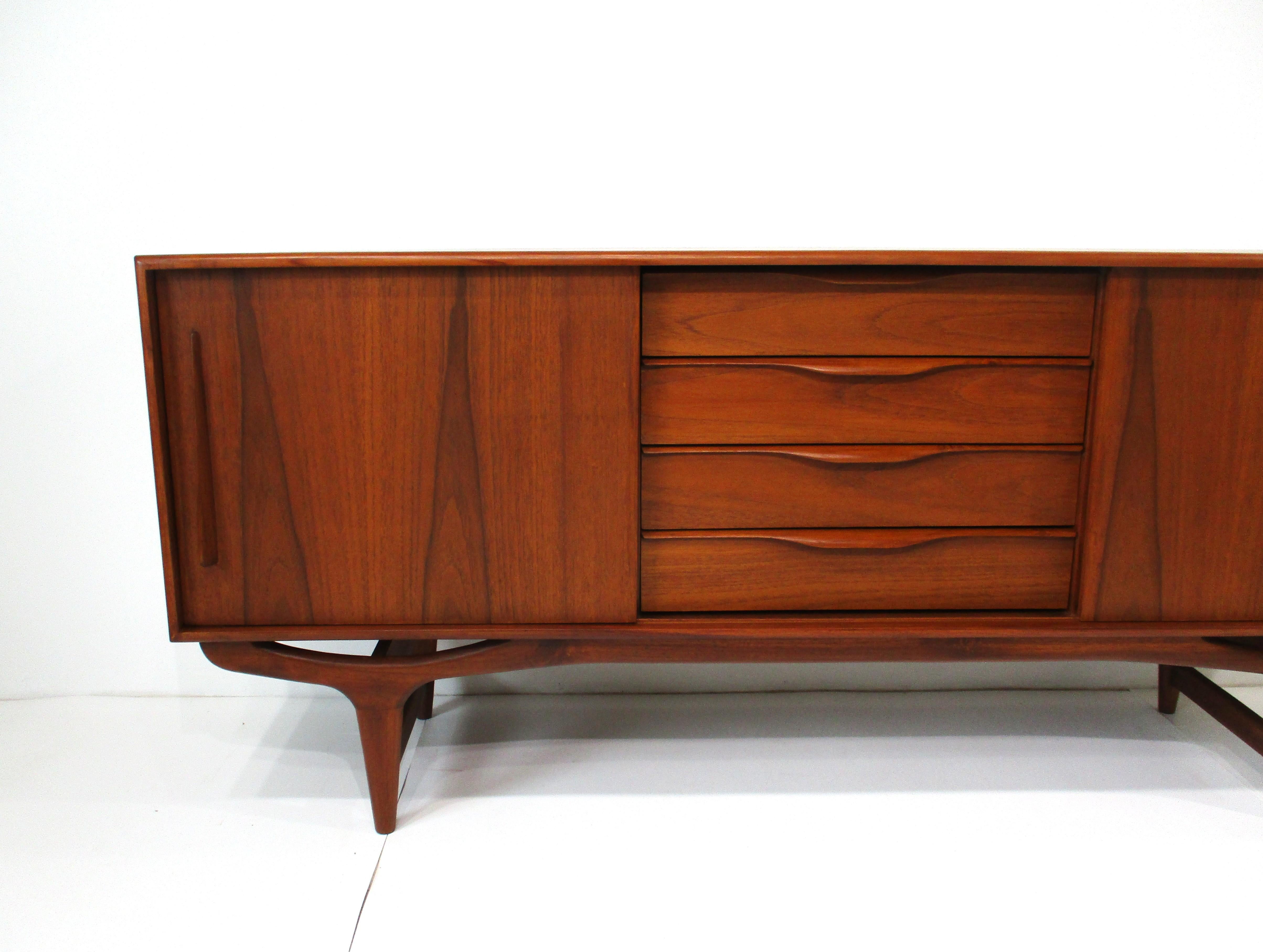A very well crafted teak wood credenza / server fashioned by the early cabinetmakers in Denmark with exceptional wood graining the doors  . Sculptural pulls to the fronts of the four drawers with stunning sculptural legs and lower stretchers to the