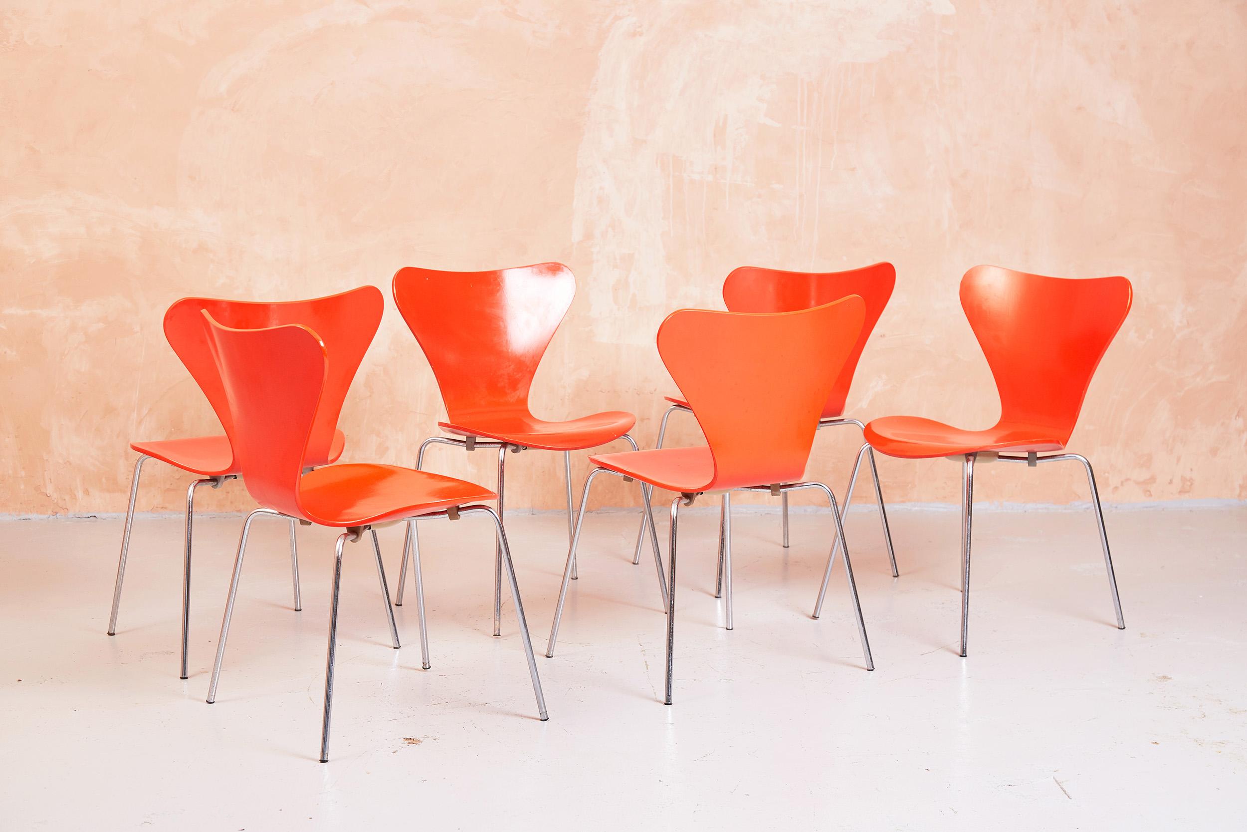 This set of 6 Model 3107, or Series Seven chairs, were designed by Arne Jacobsen and manufactured by Fritz Hansen.

The chairs are finished in the original orange paint.

The leg assembly plate on the underside of the chairs dates them as 1974,