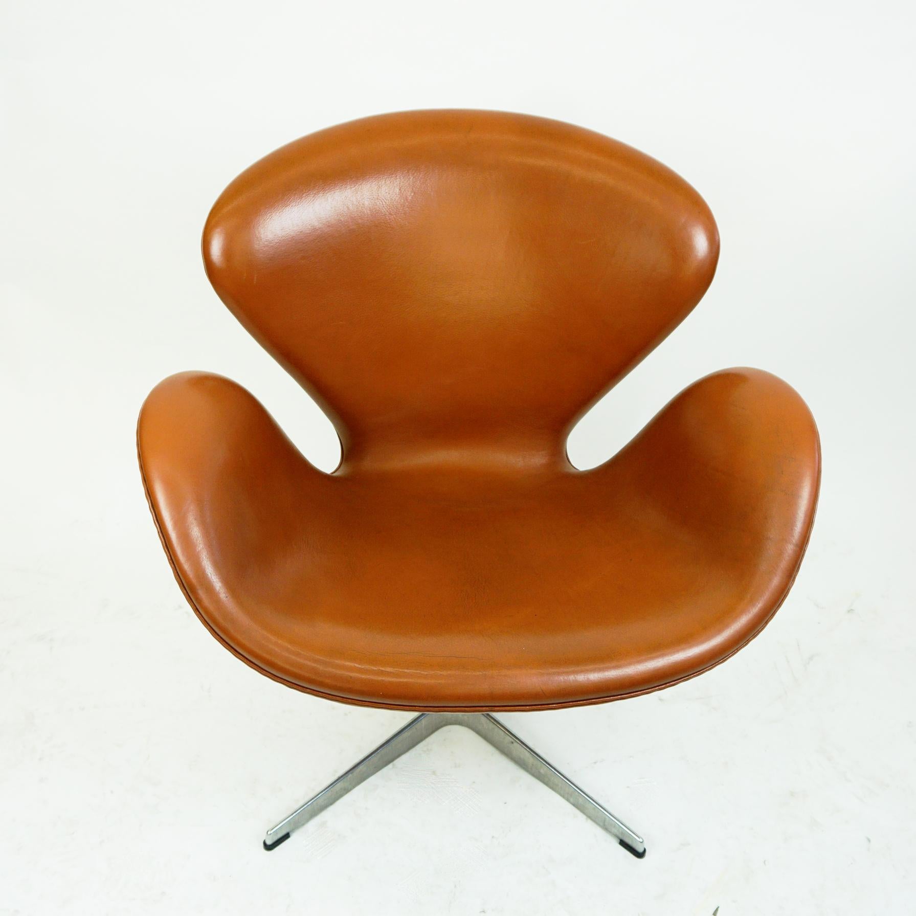 Beautiful cognac brown leather Swan lounge chairs model 3320, designed by Arne Jacobsen 1958 for the SAS Royal Copenhagen Hotel which opened in 1960. This one is produced by Fritz Hansen 2008 as you can see on it´s original label. It has a moulded