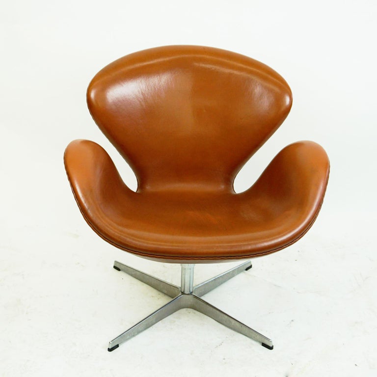 Beautiful brown leather swan lounge chairs model 3320, designed by Arne Jacobsen 1958 for the SAS Royal Copenhagen Hotel which opened in 1960. This one is produced by Fritz Hansen 2008 as you can see on it´s original label. It has a moulded fully