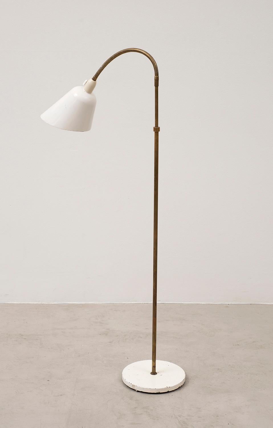 An early floor lamp by Arne Jacobsen in original condition, designed in 1929. Produced by Louis Poulsen in Denmark. Lovely patina on the painted shade and painted metal base. Shaft in original solid brass is adjustable and extends up to 5 feet in