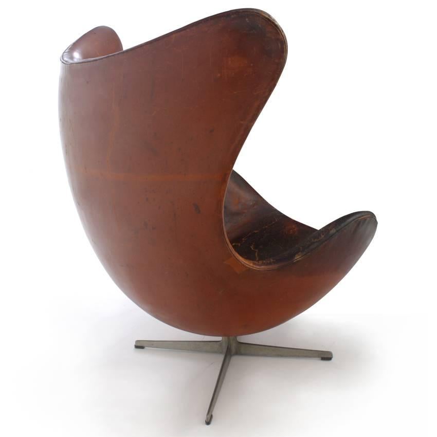 Arne Jacobsen’s iconic design Classic, the Egg Chair, was designed in 1958 for Fritz Hansen. This one is from the 1960s and has its original leather upholstery. The leather was partially repaired and the cushion is missing.