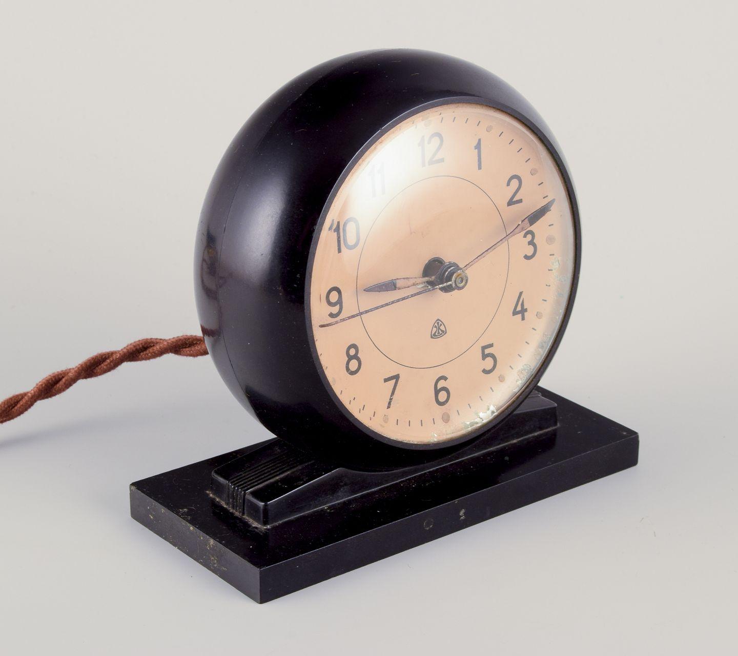 Pre-owned goods are exempt from import duties for U.S. customers. 
Therefore, no import tariffs will be applicable to your purchase.

Arne Jacobsen table clock in bakelite.
With alarm function.
Produced by Lauritz Knudsen.
Original fabric cord and