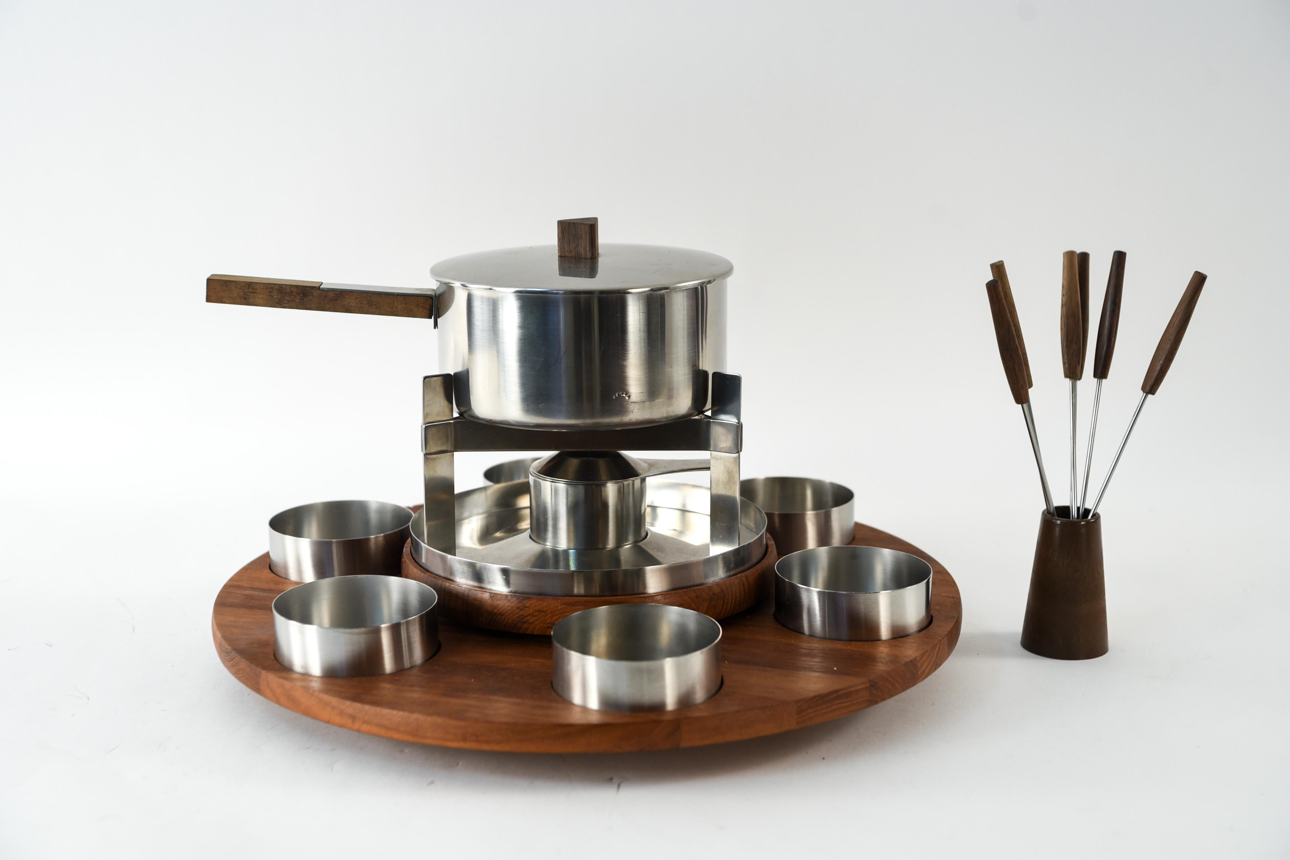 This is a fun stainless steel fondue set with wood accents, designed by Danish mid-century designer Arne Jacobsen for Stelton. This set features a fun 