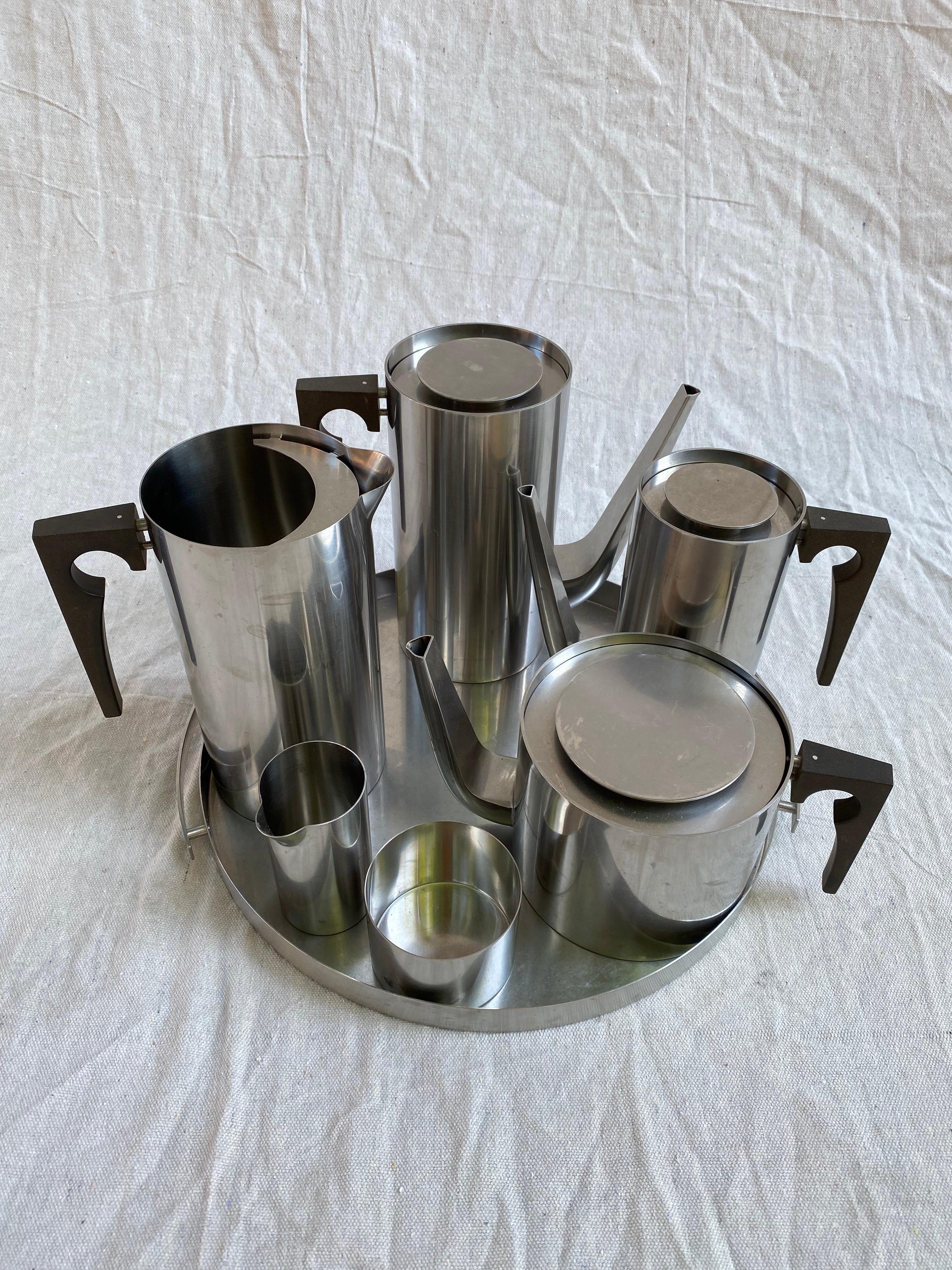 Arne Jacobsen for Stelton stainless steel coffee, tea, drink set. Includes coffee and tea pots, water pitcher, Espresso pot and cream and sugar that all fit on the round handled tray. Very nice condition, basically looks unused!