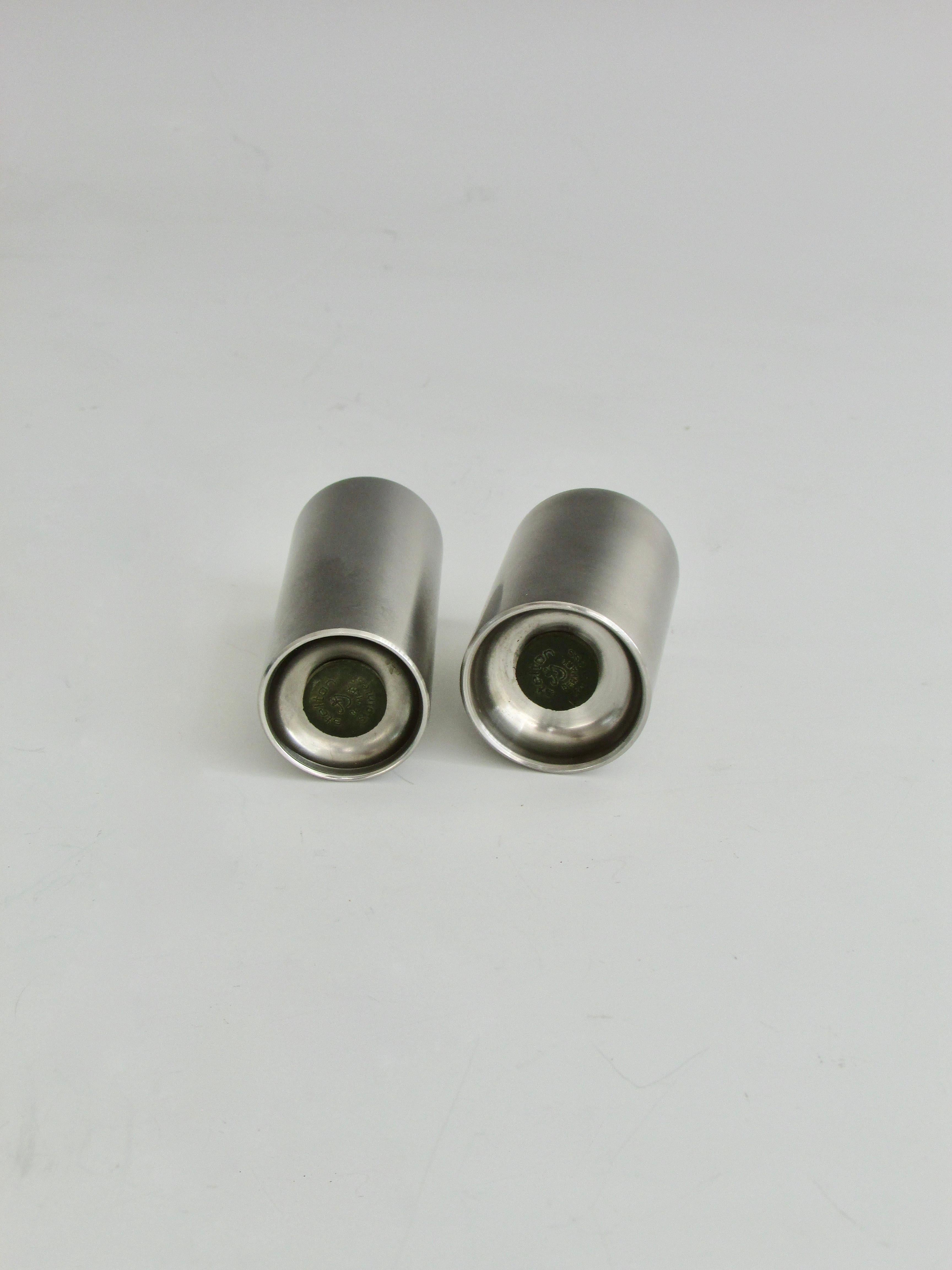 Modernist salt and pepper shakers. Cylinder form stainless steel designed by Arne Jacobsen. Both retain original rubber stoppers marked Stelton Denmark.