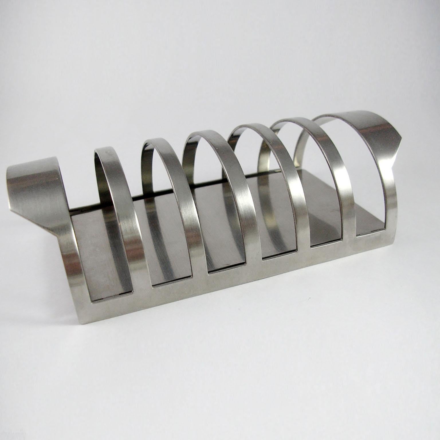 Toast rack from the 'Cylinda-Line' service, designed by Arne Jacobsen for Stelton Denmark in 1967, not anymore in production.
Made of stainless steel, barrel-shaped rack on a flat base, the handles formed as extensions to the racks at each end, the