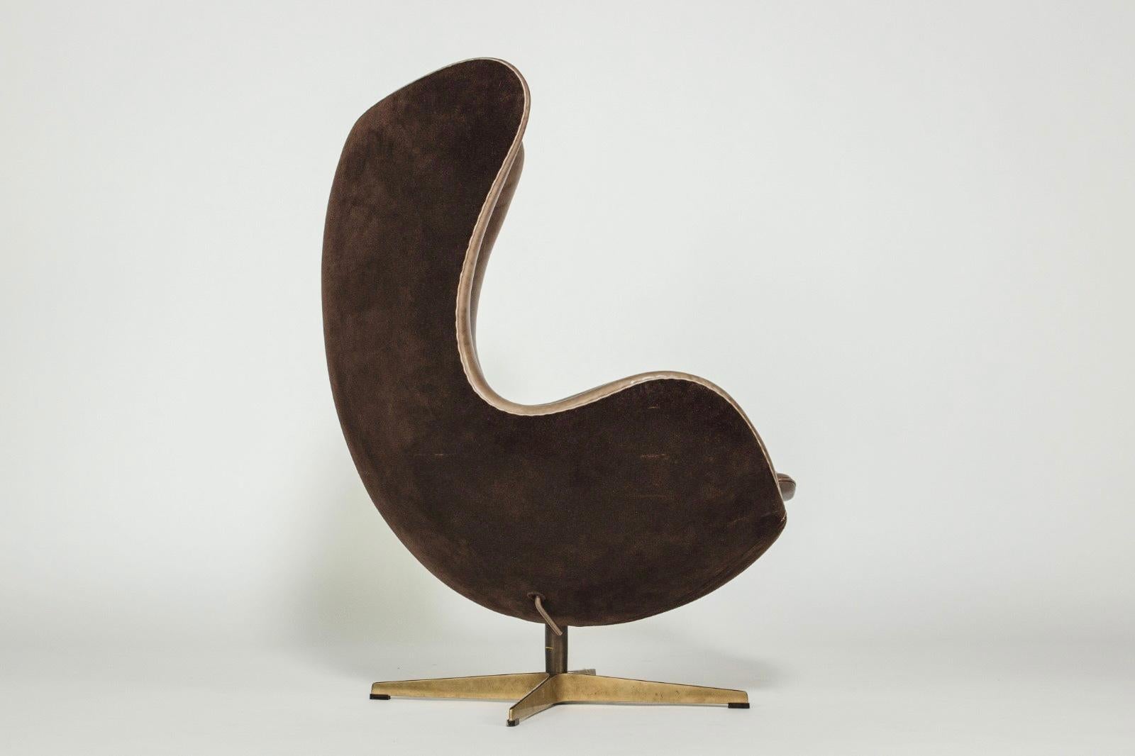 Arne Jacobsen. 'The Golden Egg' chair and footstool, models 3316 and 3127, Upholstered in dark-brown leather on the front and dark-brown suede on the back. Four-star base in solid hand-polished bronze.. Designed in 1958. Produced by Fritz Hansen in