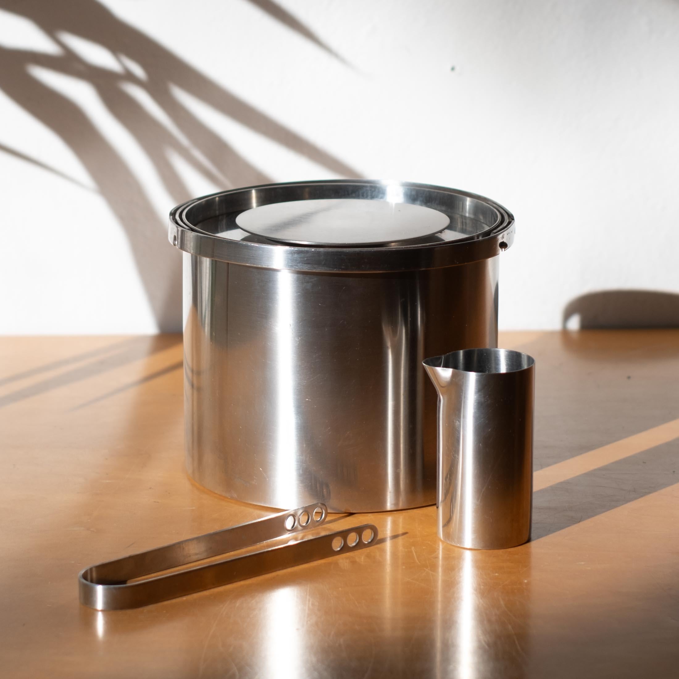 El juego de cubitera, pinzas y pequeña jarra vertedora para bar Cylinda-line está fabricado en acero inoxidable de la máxima calidad. Diseñado por Arne Jacobsen y fabricado en Dinamarca. Se trata de la primera producción e incluye la etiqueta