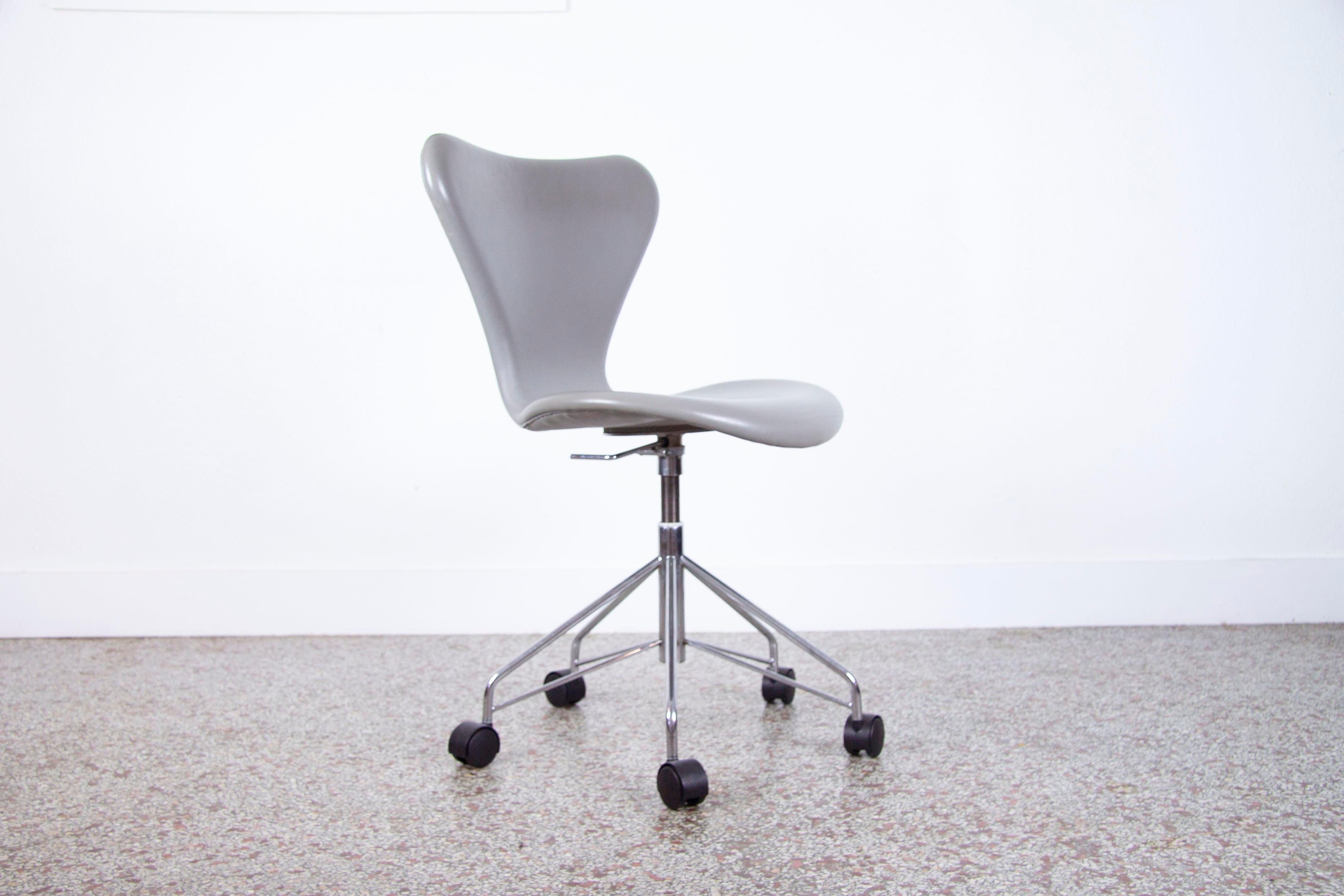Arne Jacobsen Model 3117 series 7 desk chair fully upholstered in Grey leather. Features a chrome metal base with adjustable height controls. The Series 7 range of chairs was designed in 1955 and has become one of the most iconic chair designed in