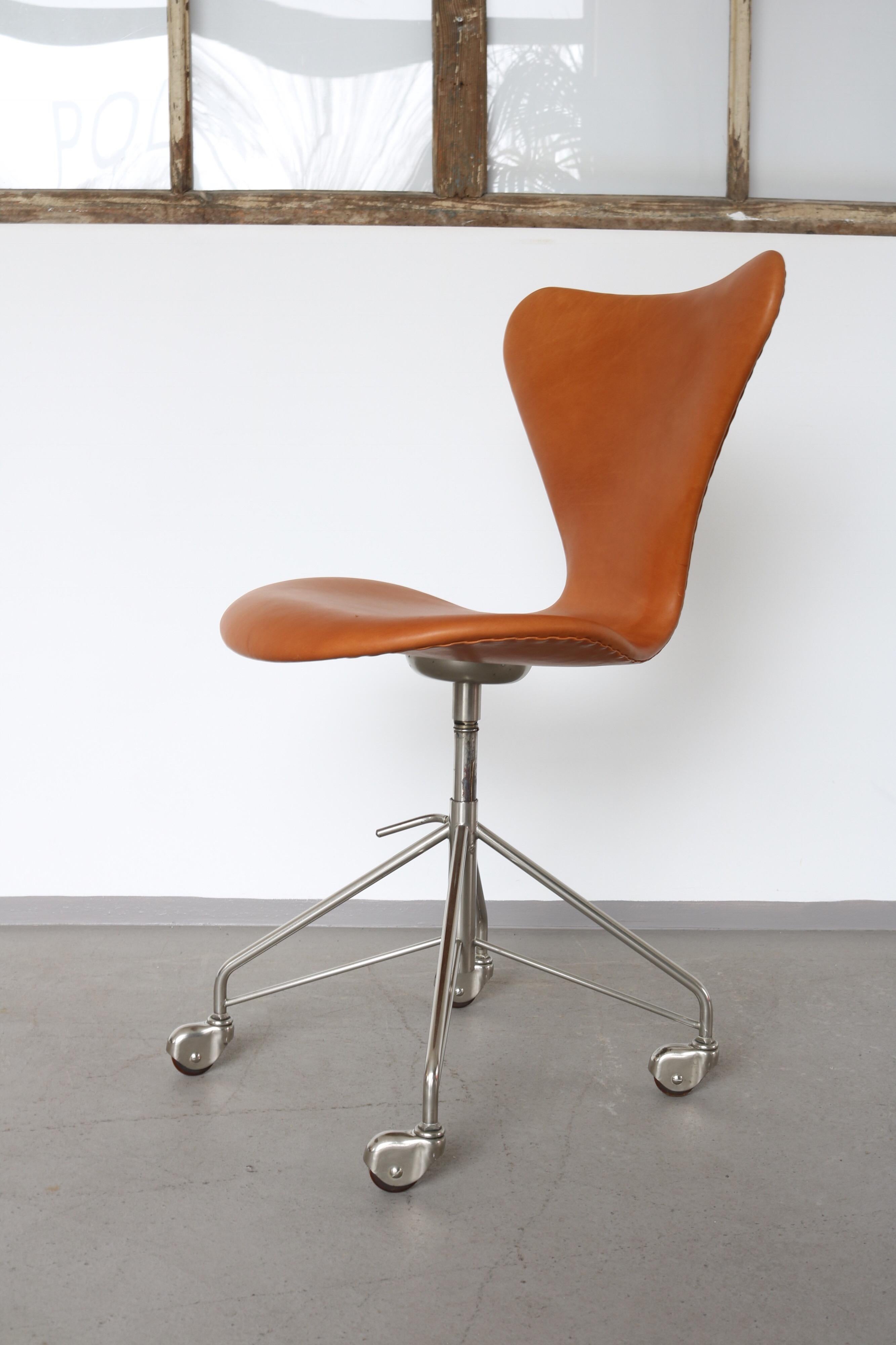 Rare Mid-Century Modern office desk chair model 3117 by Arne Jacobsen for Fritz Hansen. With the rare 4 rolls base. Reupholstered with a cognac Anilin leather. The height of the seat is adjustable.