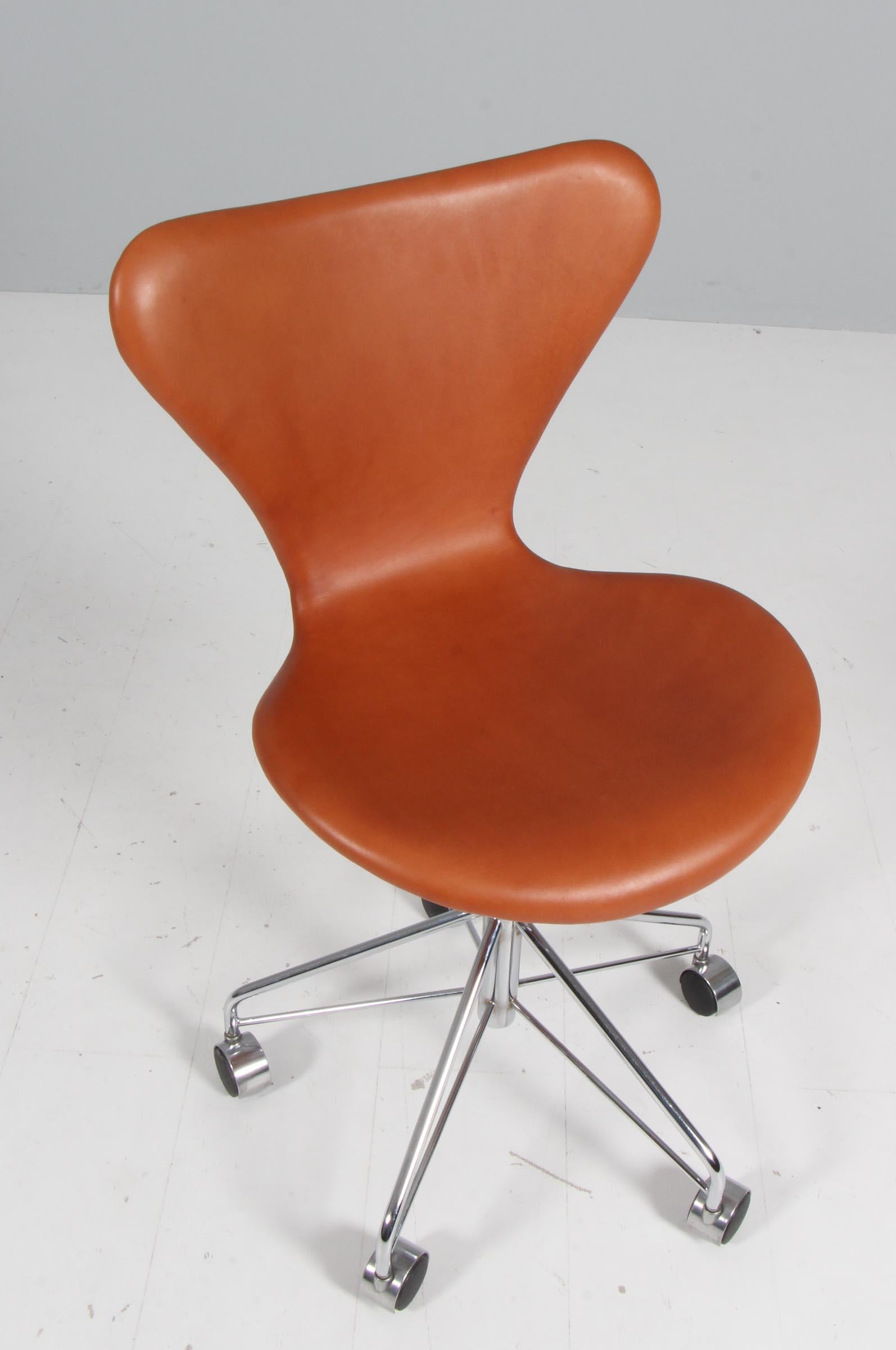 Arne Jacobsen officee chair new upholstered with cognac aniline leather.

Base of chrome steel tube.

Model 3117 Syveren, made by Fritz Hansen.