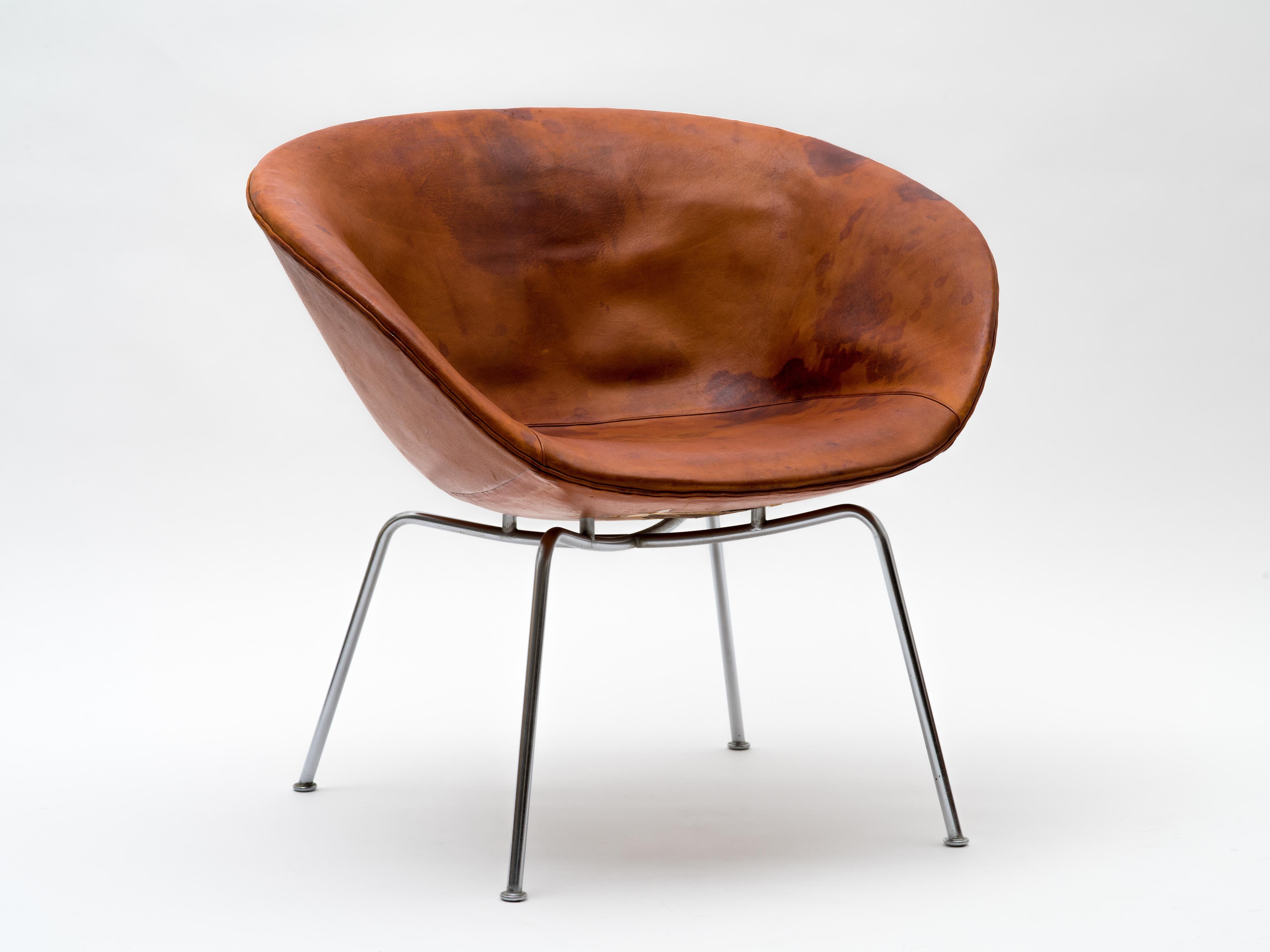 Ein Topfstuhl von Arne Jacobsen, Modell 3318, bestehend aus einem flachen Gestell mit einer schalenförmigen Sitzfläche, die über vier verchromten Stahlbeinen schwebt. Ein täuschend geräumiger und bequemer Stuhl, den Jacobsen 1959 zusammen mit den