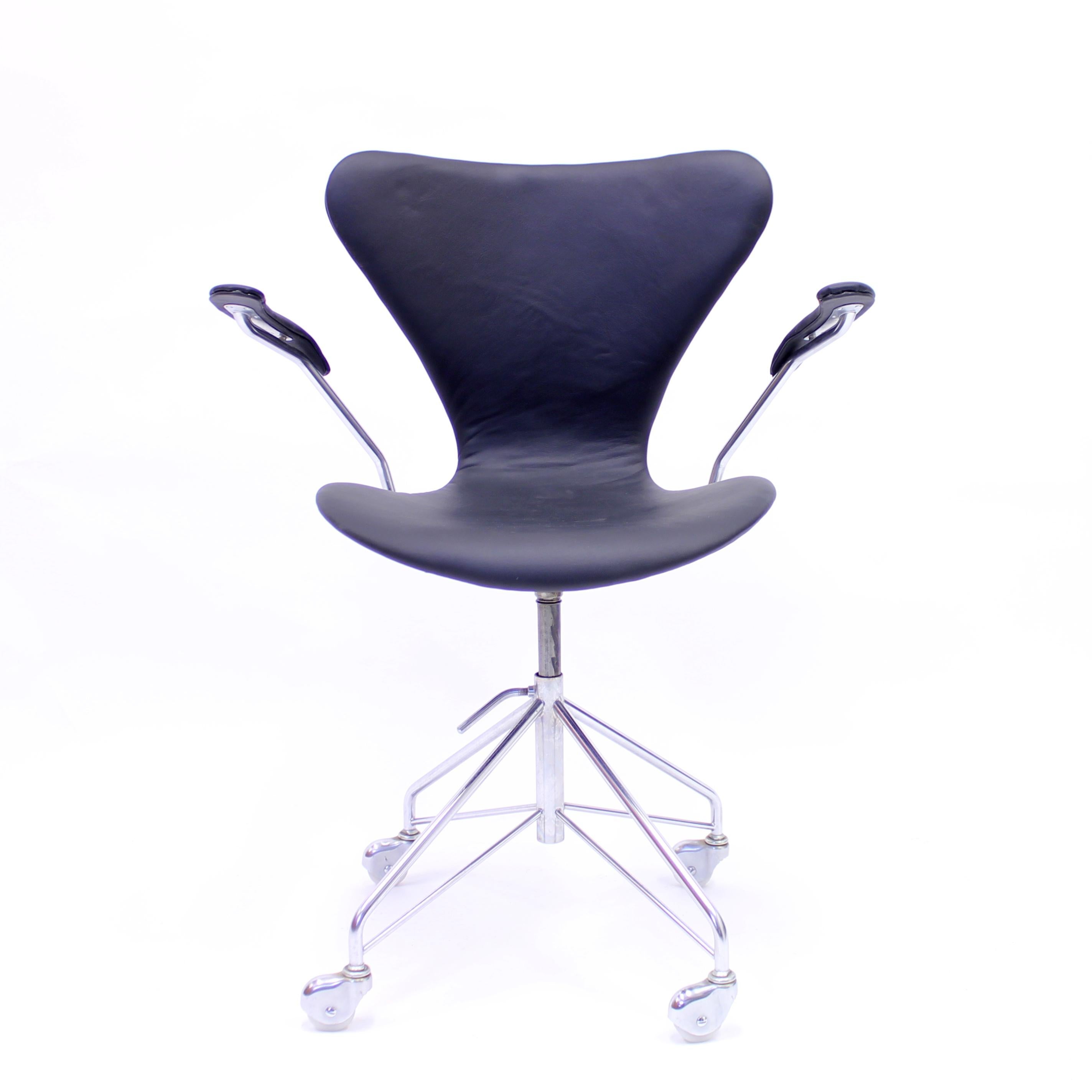 Early production Series 7 office chair with armrests, model 3217, designed by Arne Jacobsen for Fritz Hansen. The base has a swivel function and the seat is height adjustable between 45-58 cm. New black leather upholstery, four-wheel base. This